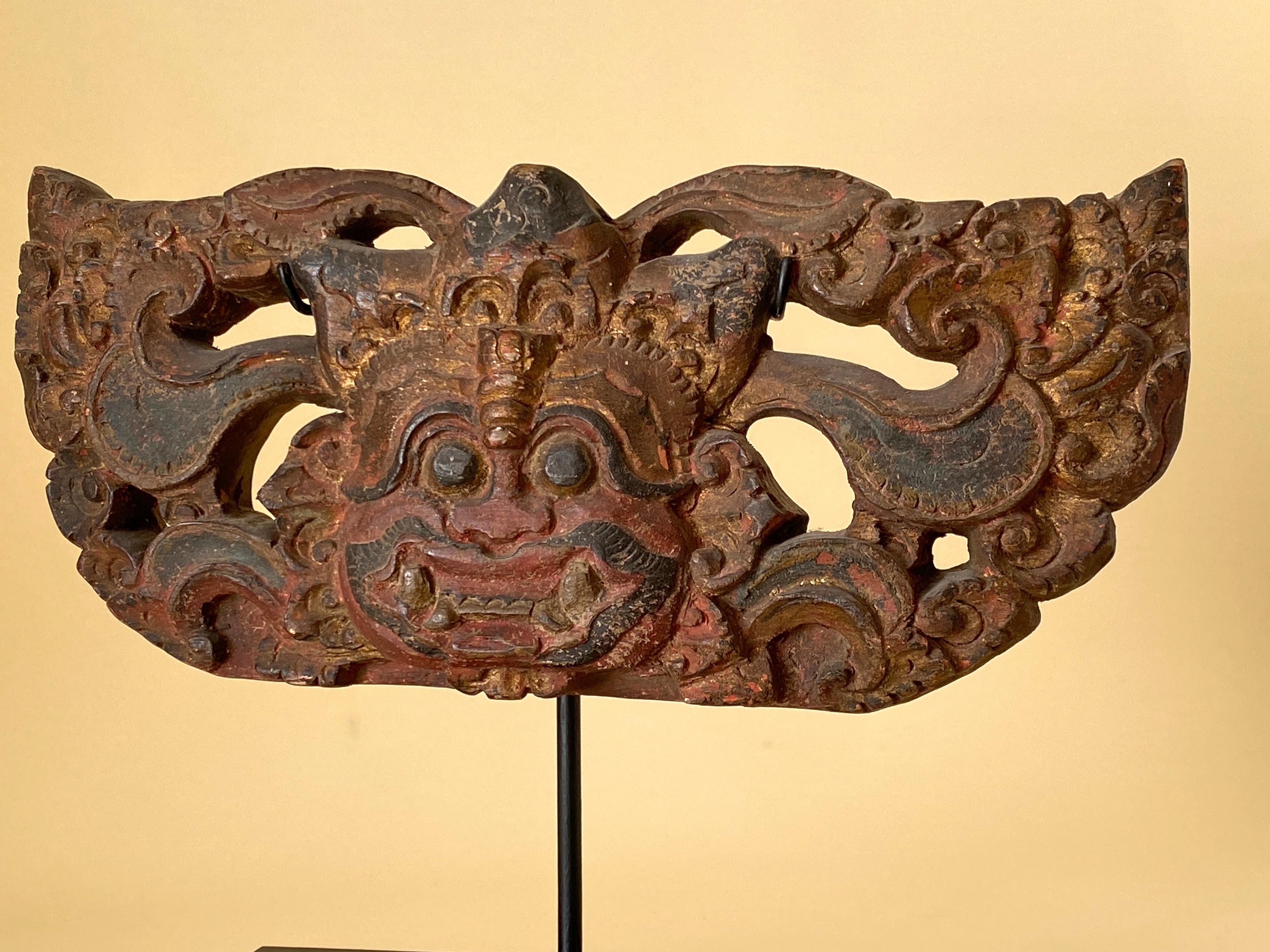 A delightful door or threshold guardian figure, called Boma (alt. Bhoma), from Bali, Indonesia, early 20th century. Wood with pigments, mostly red and black with some gold.
Boma are fearsome heads surrounded by foliate scrolls placed on lintels
