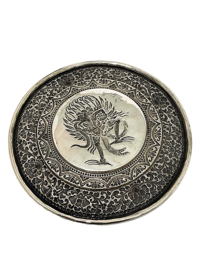 Balinese Yogya silver plate with Garuda Bird

An Indonesian Yogya plate from Bali, early 20th Century with the Garuda Bird in the center on a hammered background, surrounded with 2 beautifully decorated rings in height difference. Beautifully