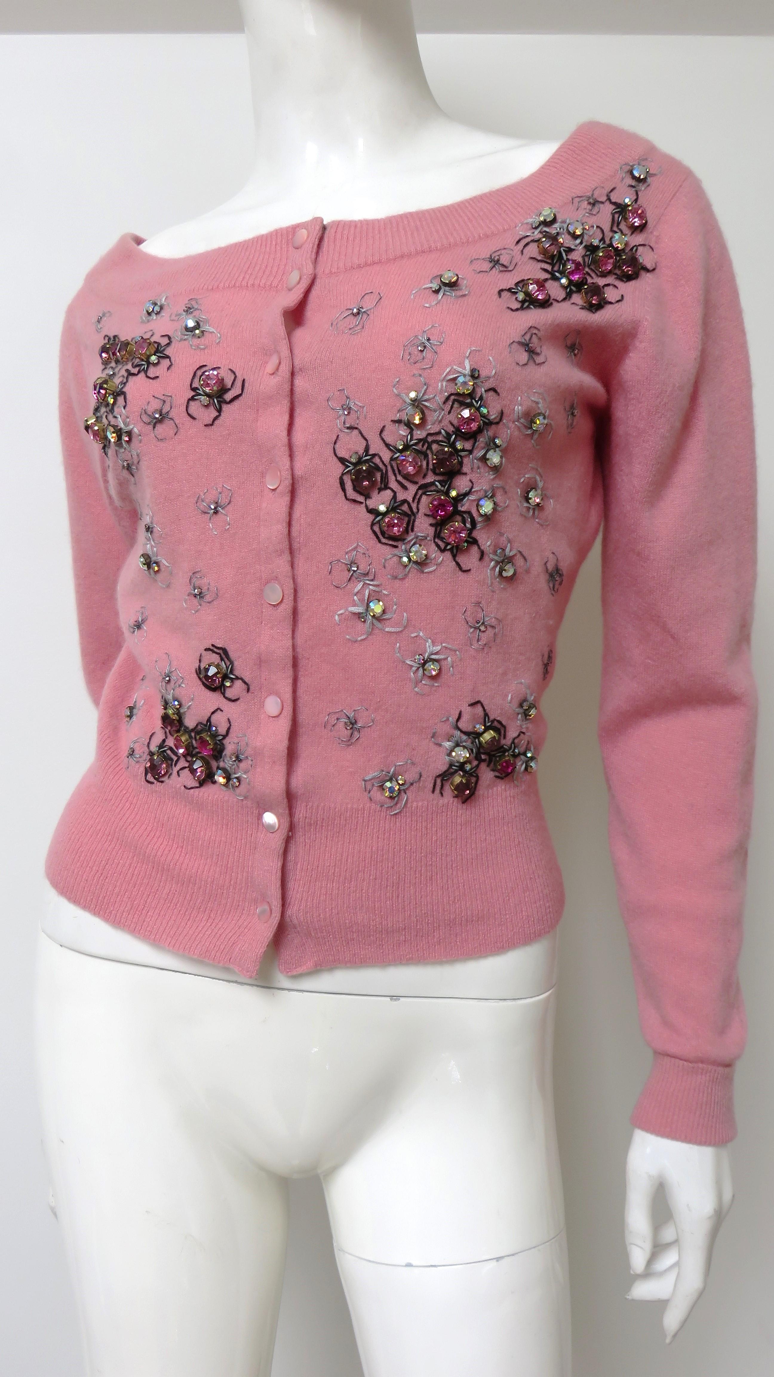 A gorgeous pink cashmere cardigan sweater from Ballantyne.  It has a scoop neckline, long sleeves with fold back cuffs, and matching mother of pearl buttons up the front.  It is adorned with beautiful rhinestone ladybugs in shades of pink with