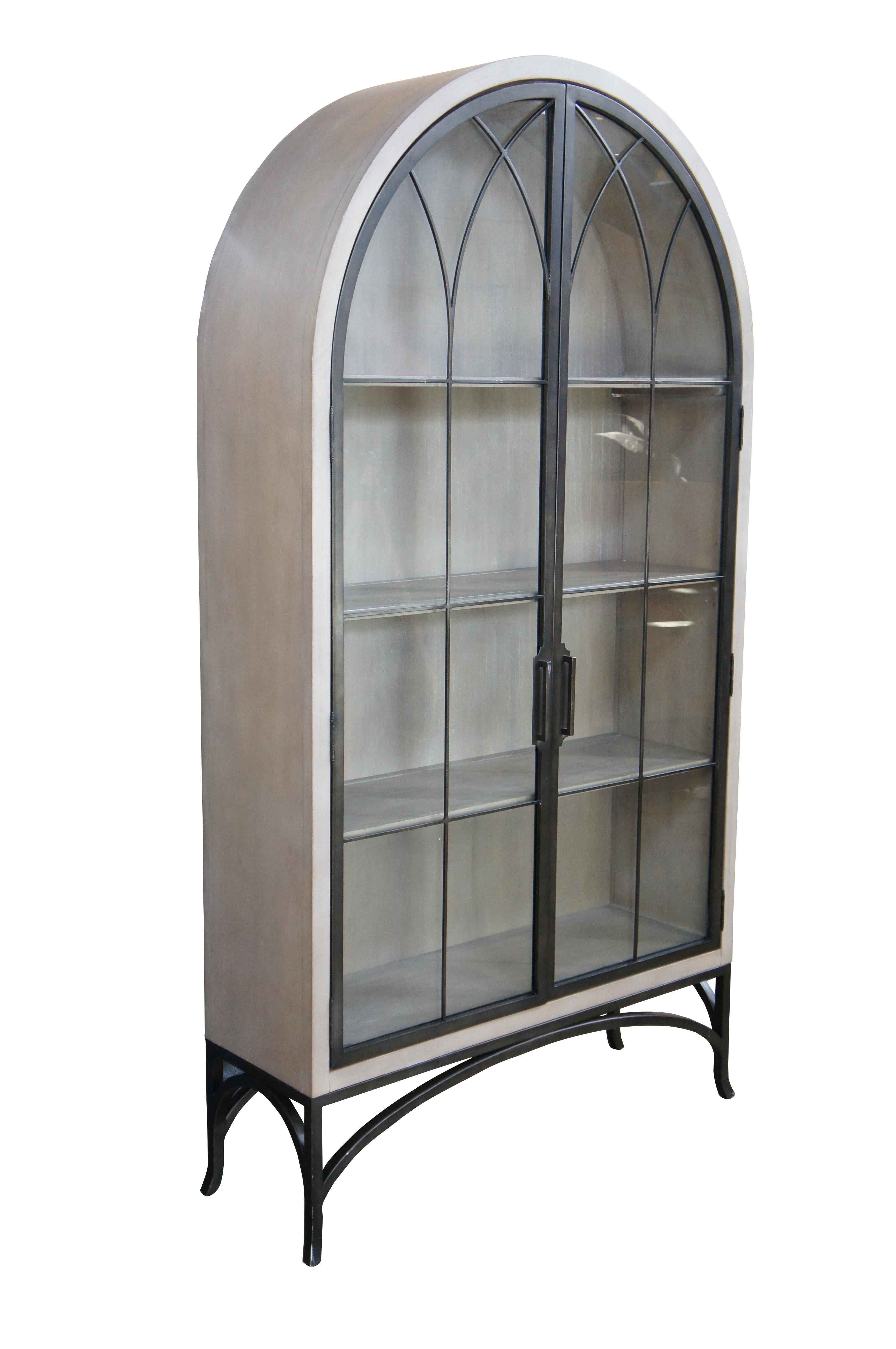The Aris Glass Door Cabinet was inspired by a graceful European Gothic window. The cabinet features a white washed finish with custom-welded, bronze metal frame doors and matching splayed feet. Slender silhouette and shallow 14