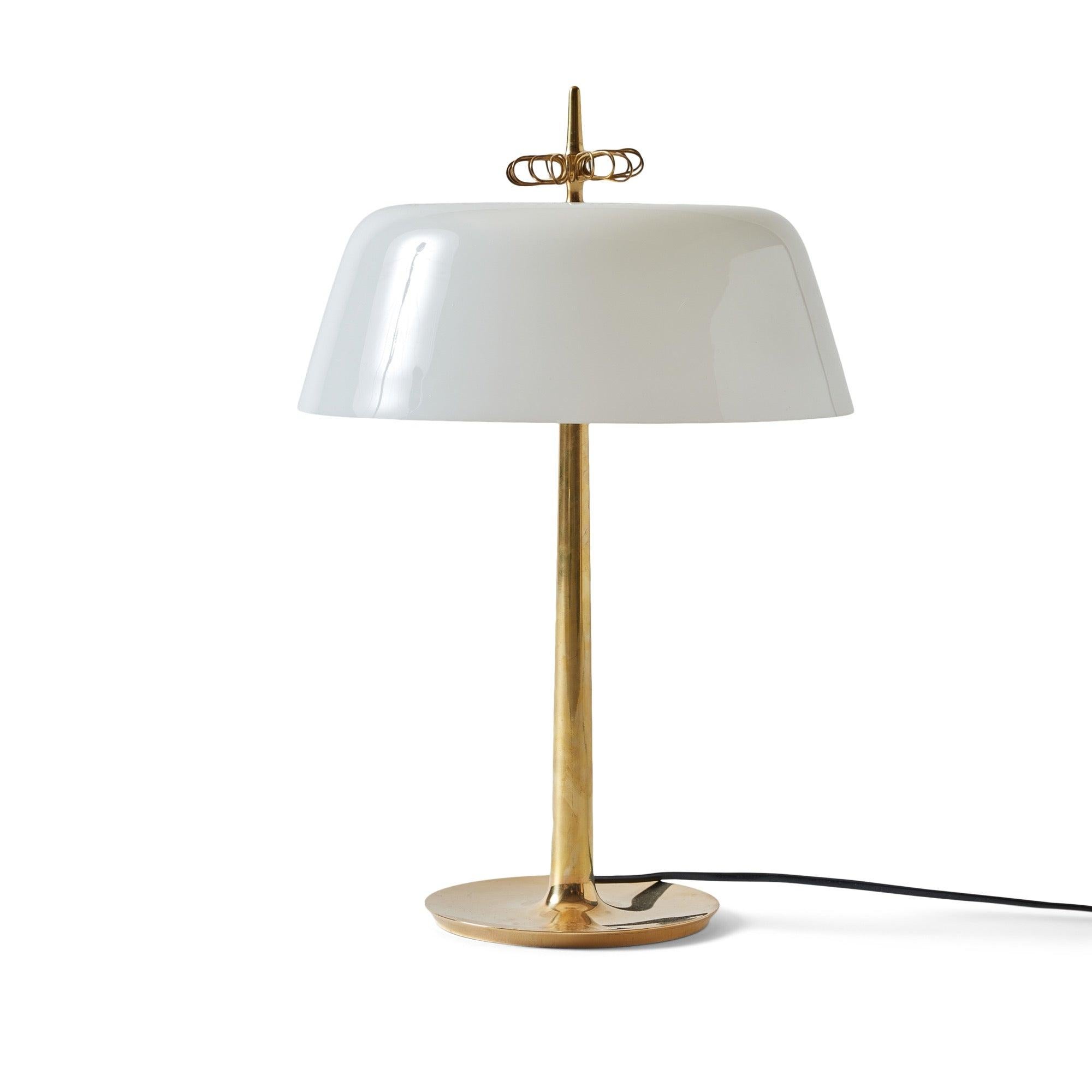 Rare table lamp, model 9211, designed by Paavo Tynell and crafted by Taito in Finland during the 1950s. The lamp features a cast brass body with a smooth, seamless design, paired with a rounded white opal glass shade crowned by a brass flower detail