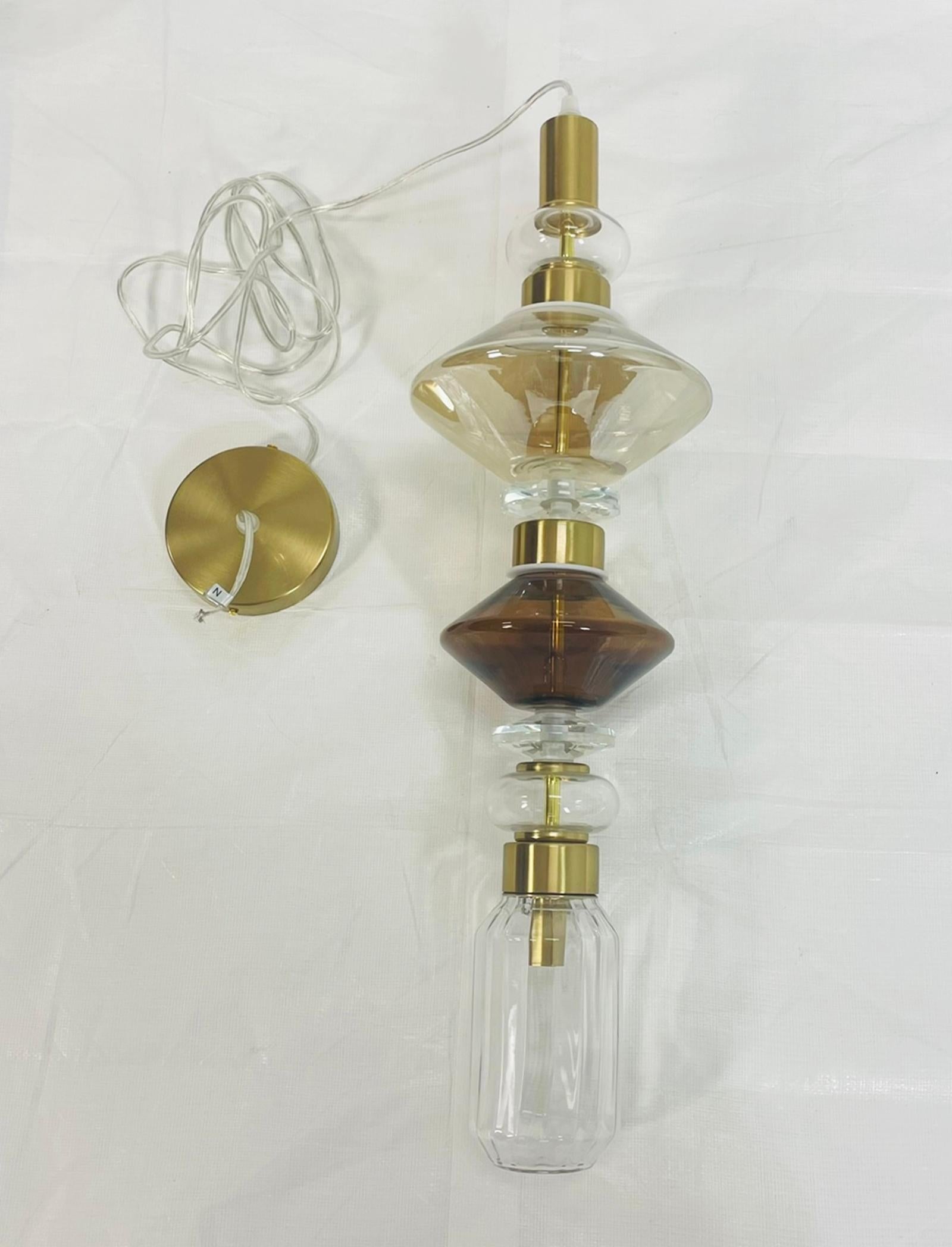 Pendentif raffiné et sculptural de la collection Ballet, conçu par Massimiliano Raggi pour Sicis et fabriqué à la main en Italie. Le modèle Ballet No. 2 présente une composition sophistiquée de verre soufflé clair, ambré et fumé, disposé en