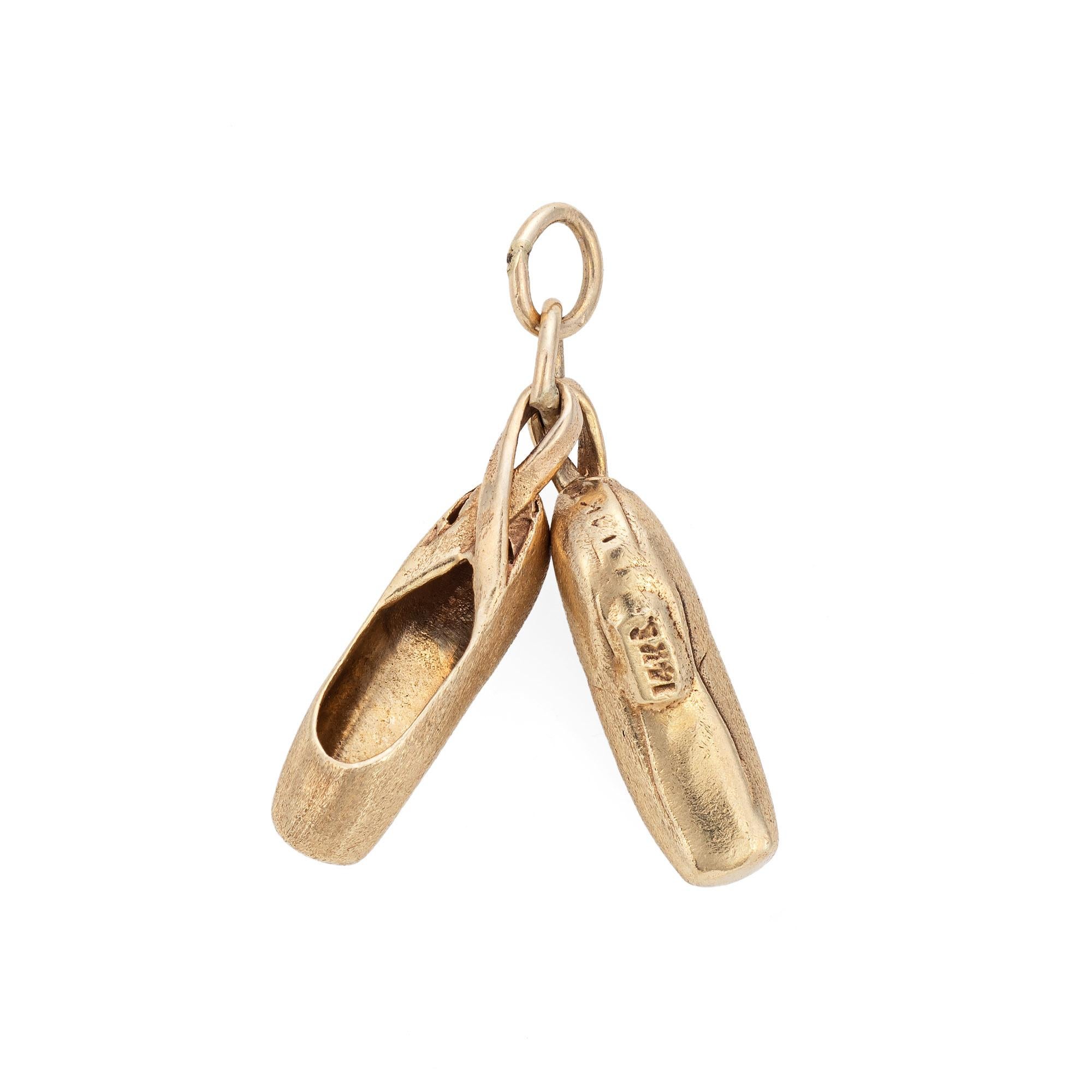 Finely detailed pair of vintage ballet slippers charm crafted in 14k yellow gold.  

The nicely detailed ballet slippers feature a satin finish for a muted gold effect. Small in scale the slippers are hollow and light to the touch at 2.8 grams.