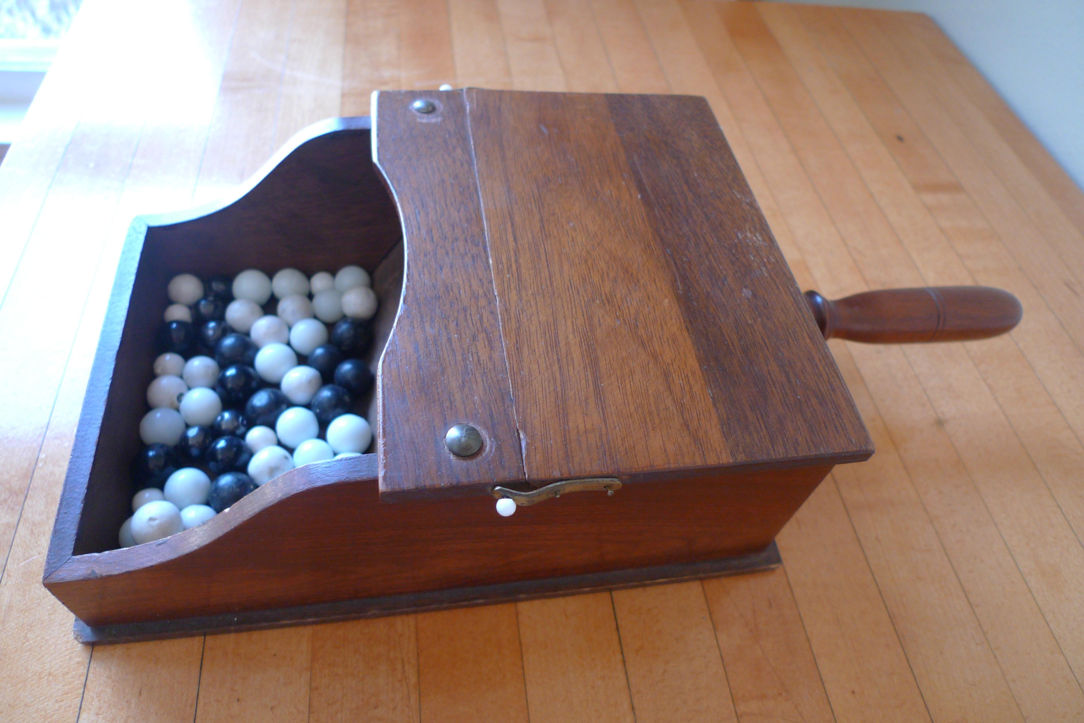 Ballot box with white and black glass balls in hand-held, lidded walnut box. Vote them on or off the island. Perfectly unique, fun, holiday gift.