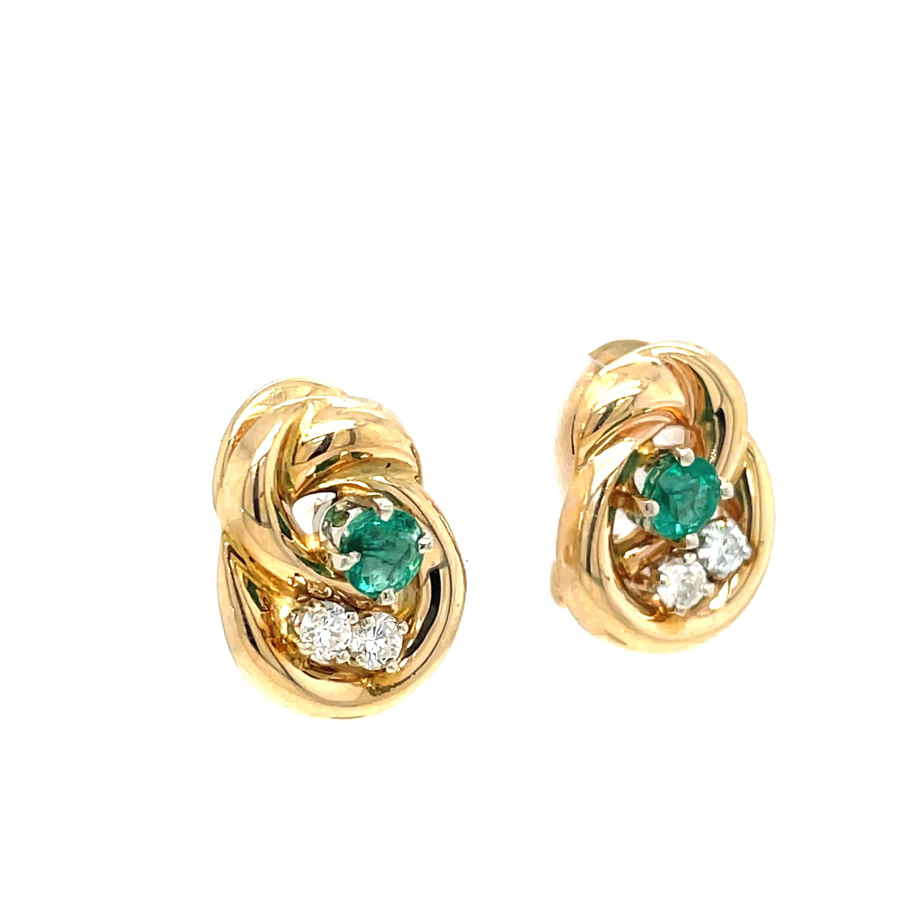 Beautiful natural emerald and diamonds are nestled in a swirl of vibrant 14 karat yellow gold crafted in a knot style giving understated elegance to this gemstone earring pair. For pierced ears with convenient and secure gold post and Omega clip,