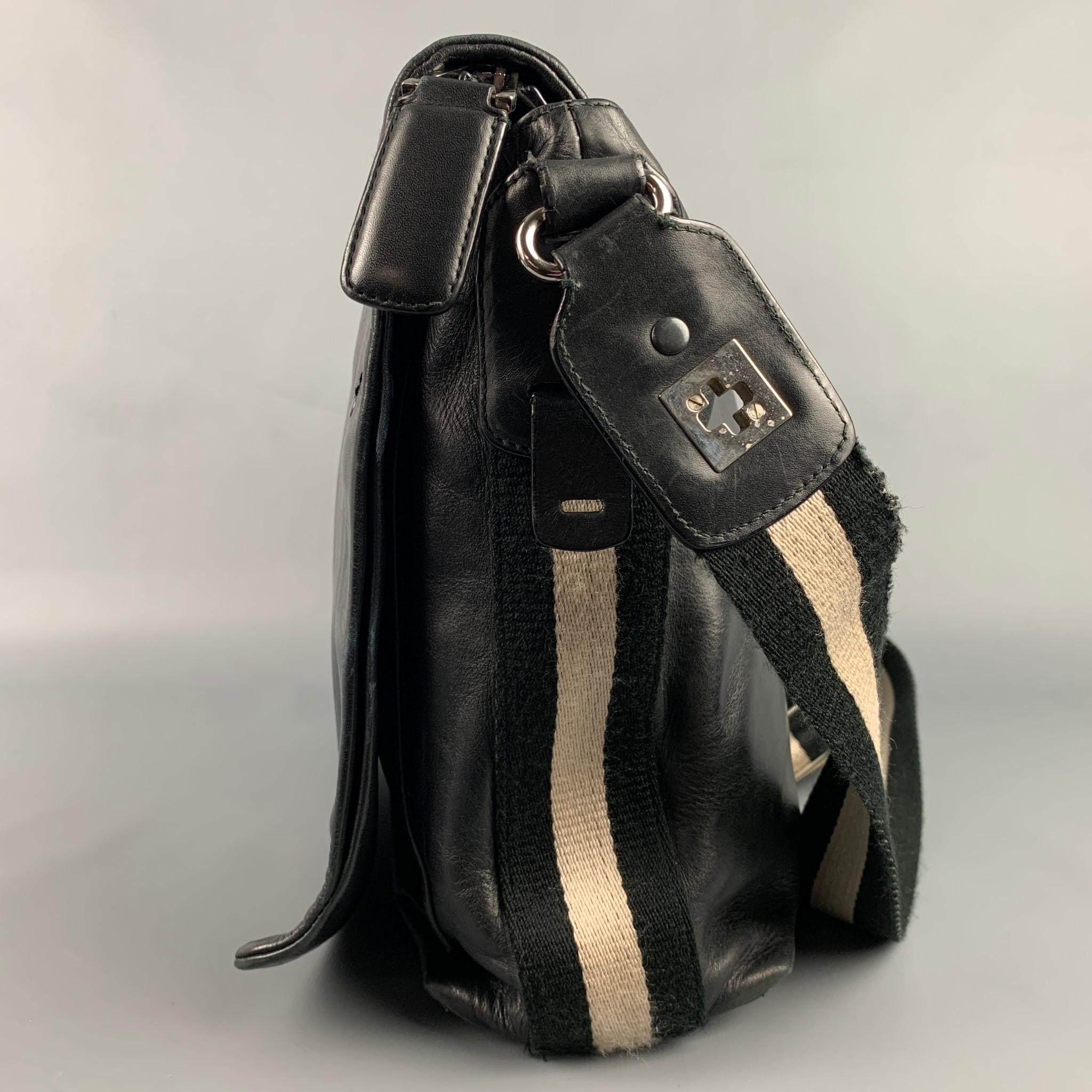 BALLY bag comes in a black leather featuring a messenger style, shoulder strap, stripe trim, front flap design, silver tone hardware, inner compartments, and a zipper closure. Made in Switzerland. 

Good Pre-Owned Condition.

Measurements:

Length: