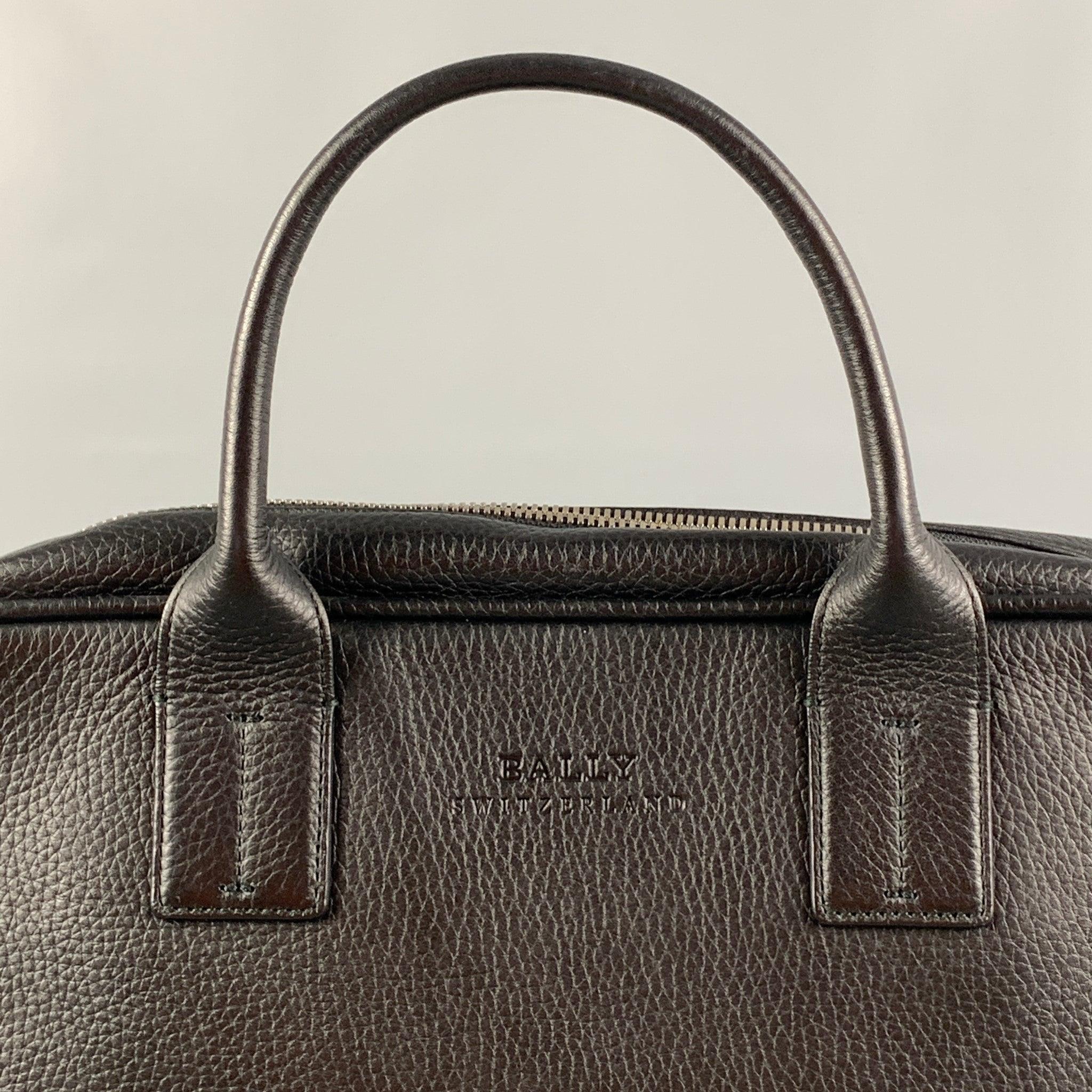 BALLY bag comes in a black leather featuring top handles, silver tone hardware, detachable shoulder strap, inner slots, and a zipper closure.
Excellent
Pre-Owned Condition. 

Measurements: 
  Length: 14.5 inches Width: 3 inches Height:
11.5 inches