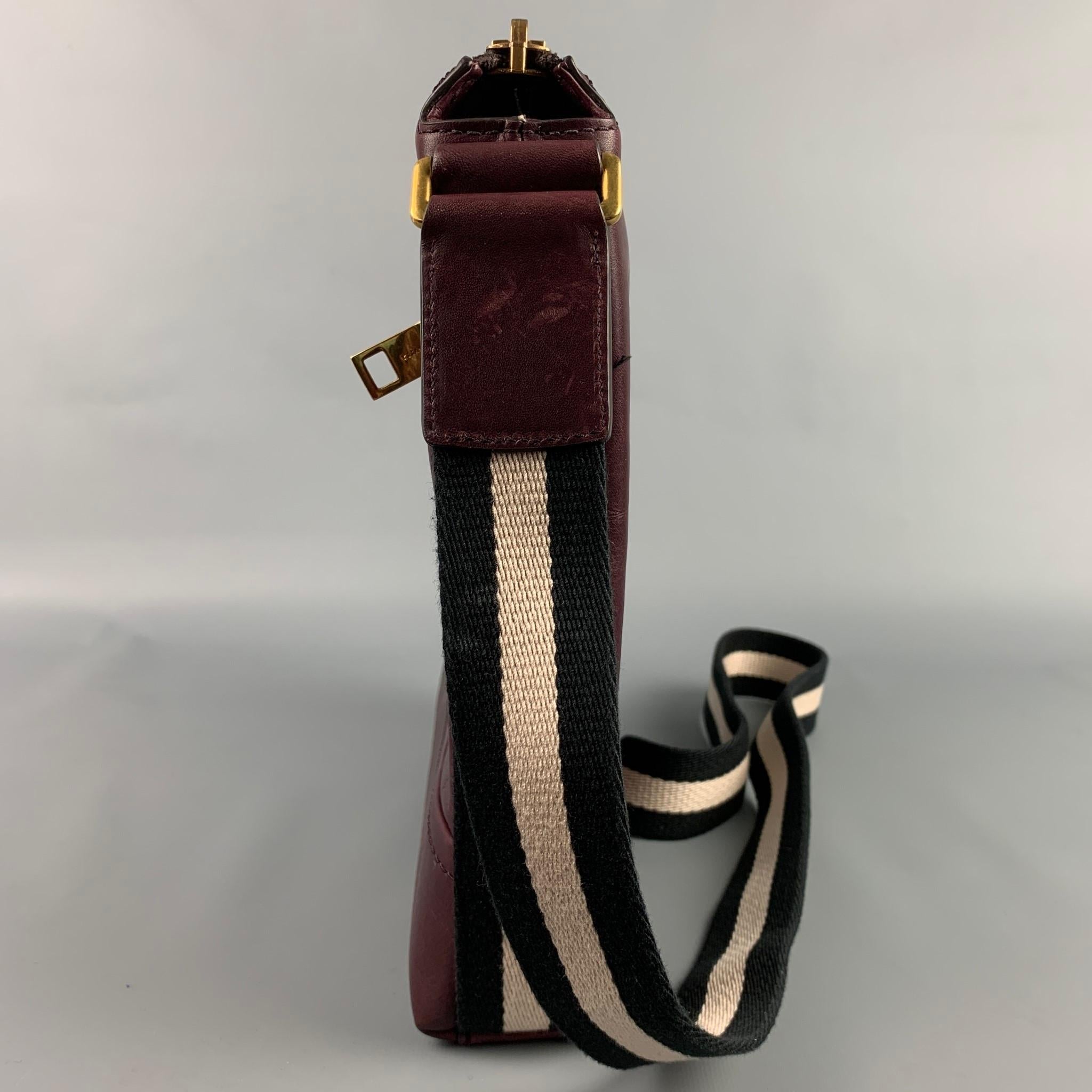 BALLY bag comes in a burgundy leather featuring a cross body style, gold tone hard ware, stripe trim, front pocket, inner pocket, and a zipper closure. 

Good Pre-Owned Condition.

Measurements:

Length: 9.5 in.
Width: 2 in.
Height: 10 in.
Drop: