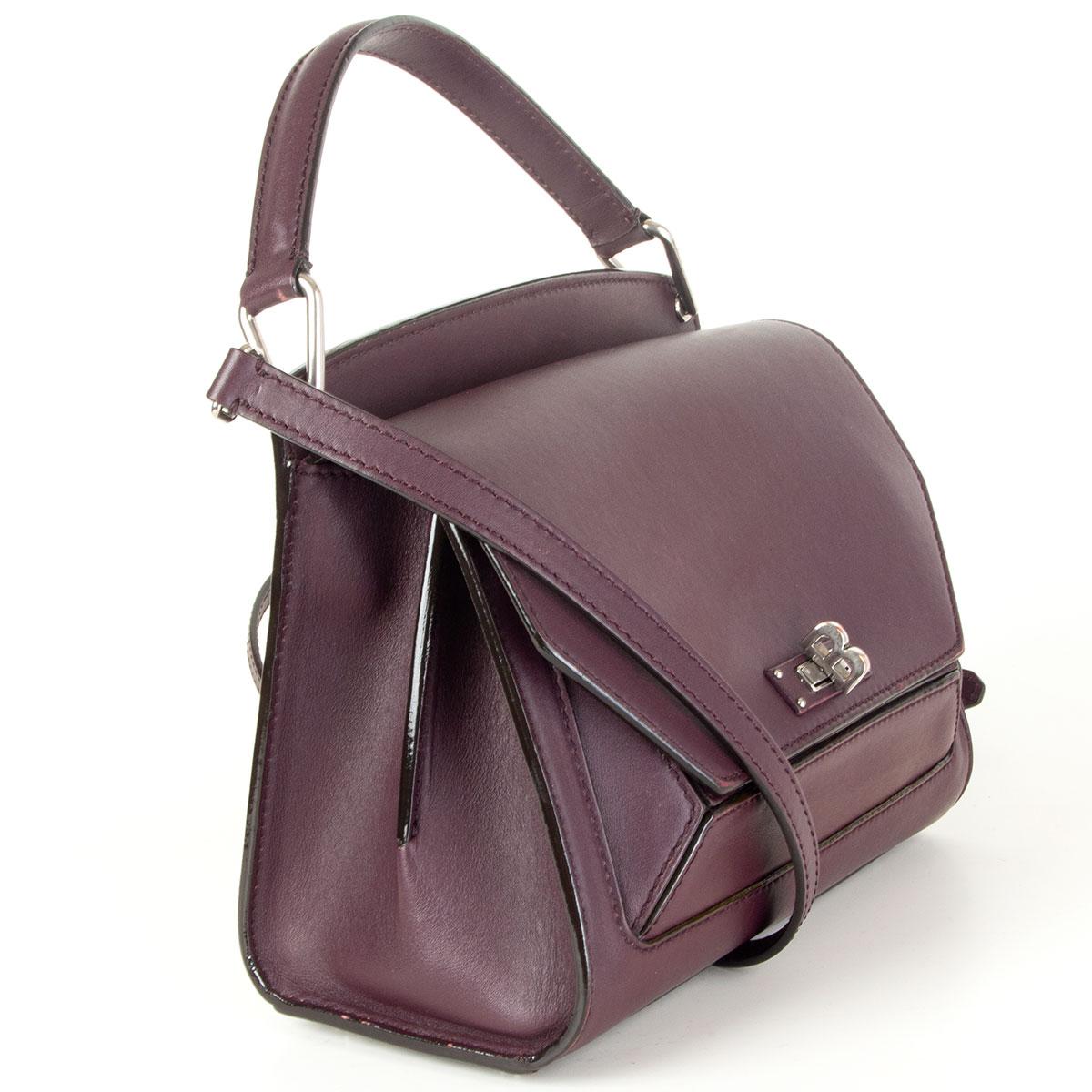 Bally B Turn satchel bag in eggplant calfskin featuring silver-tone hardware. Opens with the B turn-lock and is lined in grey microfibre with one zipper and open pocket against the back. Slit pocket on the back and under the flap. Comes with a