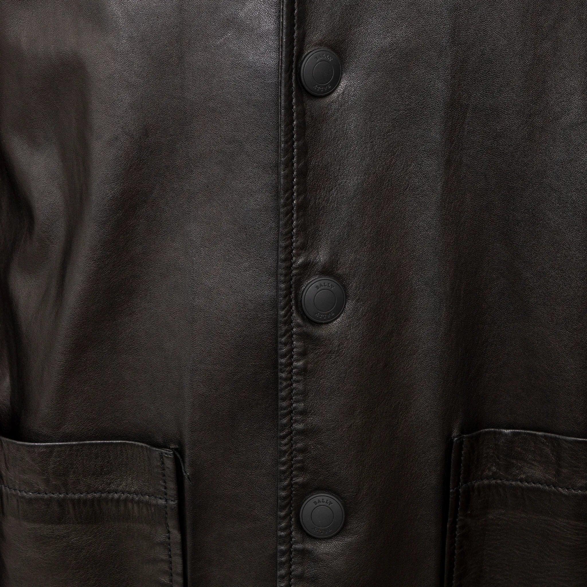 Veste en cuir Bally en cuir noir. Demi-doublure en coton avec doublure en acétate logotypé sur les manches. Boutons à logo mat, col à boutons-pression et 3 poches sur le devant.
 Remarques : Il y a une déchirure dans le coin de la poche droite.