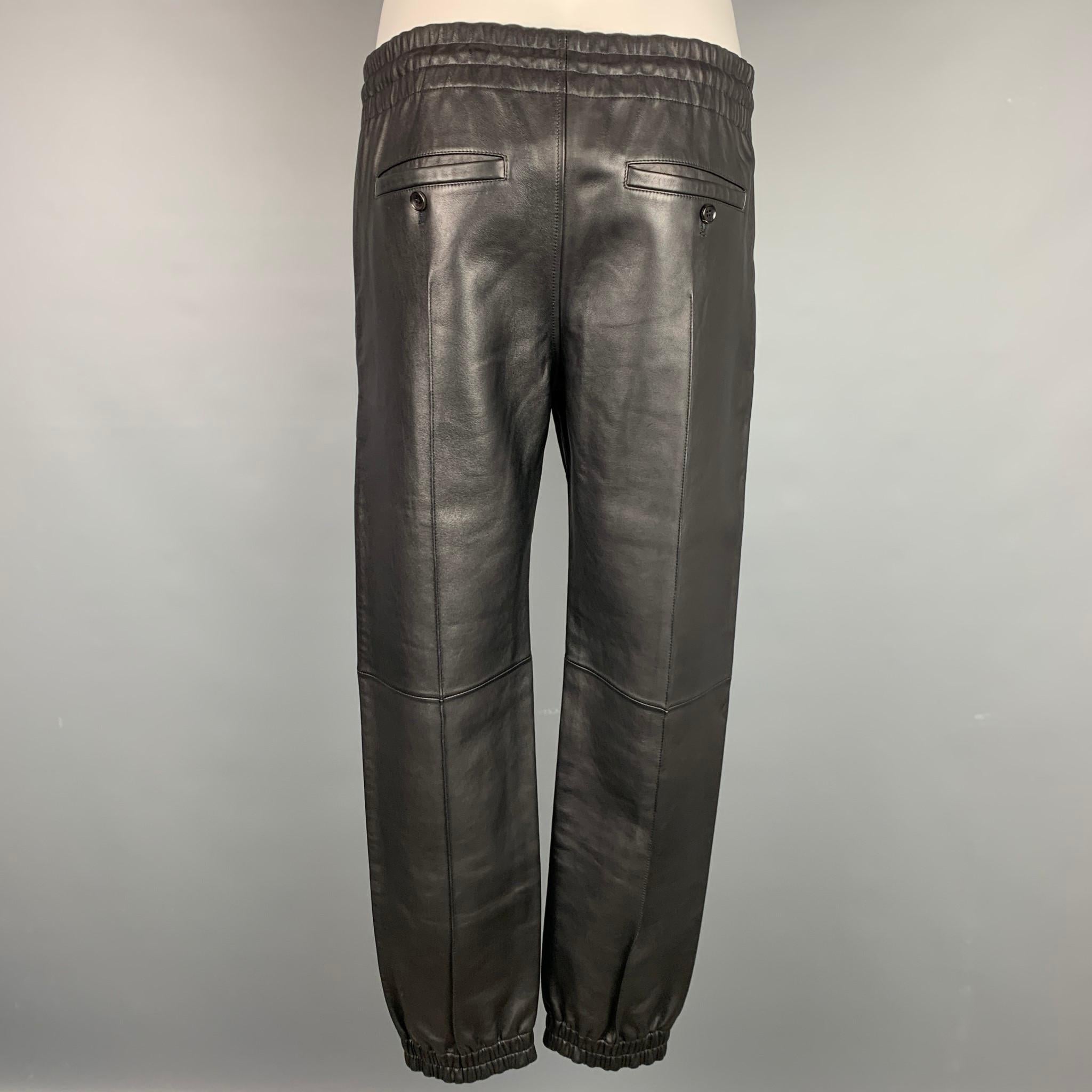 BALLY casual pants comes in a black leather featuring a elastic waistband, top stitching, and a drawstring closure. Made in Italy.

New With Tags. 
Marked: 46
Original Retail Price: $2,395.00

Measurements:

Waist: 28 in.
Rise: 11.5 in.
Inseam: 27