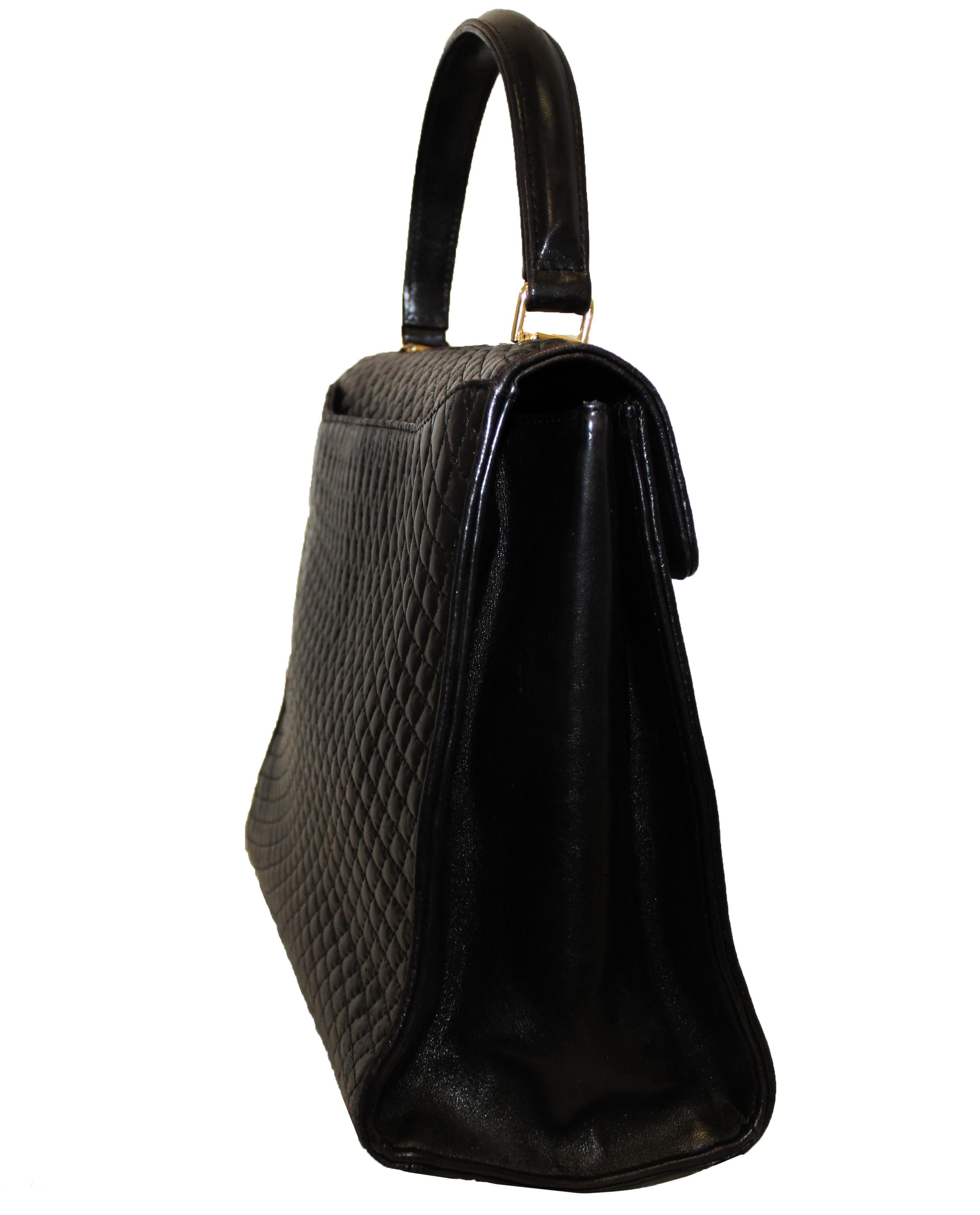 Bally Vintage black top handle bag was created with premium supple leather in a quilted pattern.  With a single flap that contains a covered top handle and for closure a turn lock clasp at flap.  The hardware Is gold tone. One exterior open slit
