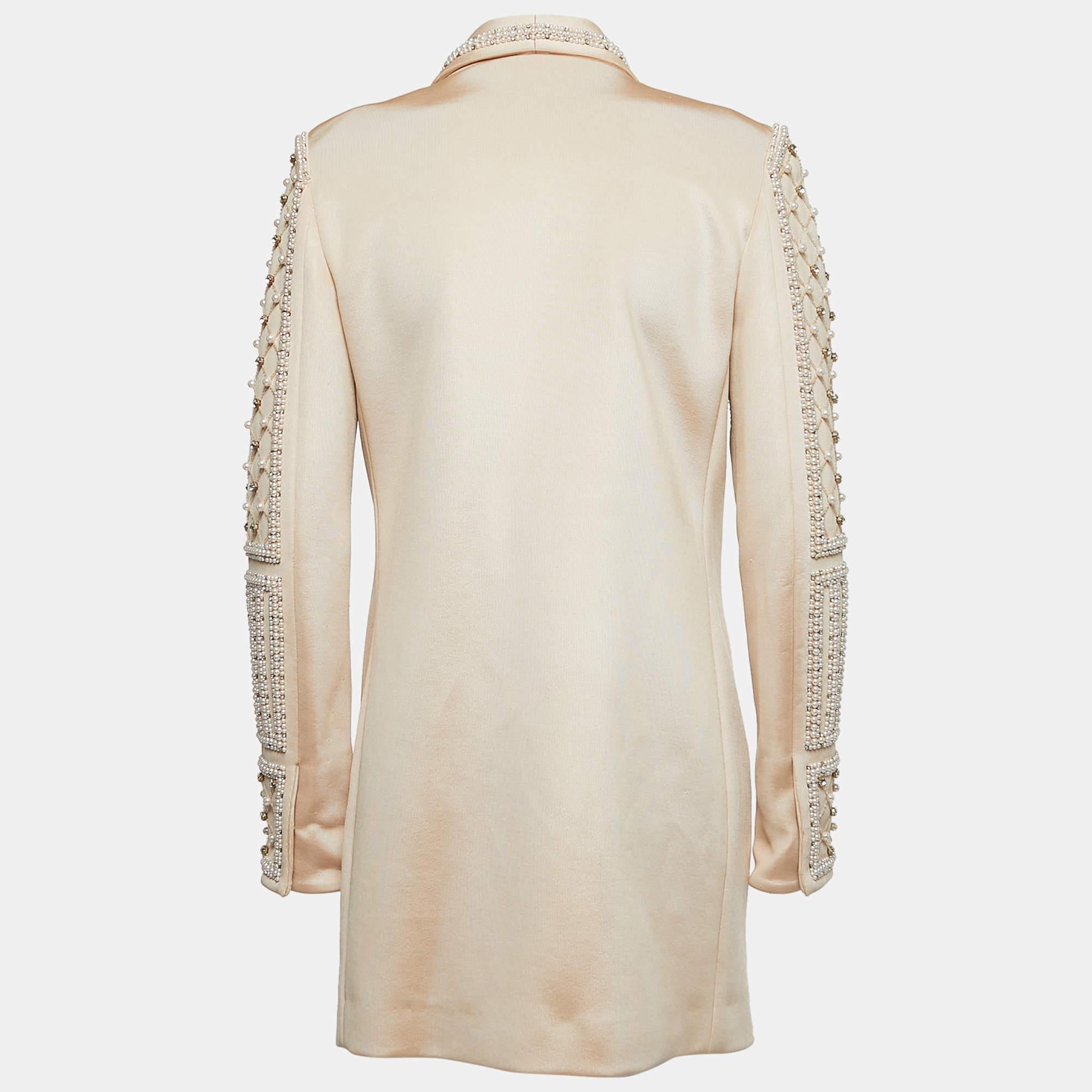The Balmain blazer is a luxurious fashion piece. It features a sophisticated beige hue with exquisite crystal and pearl embellishments, creating a stunning visual appeal. The shawl lapel adds elegance, making it a perfect choice for evening