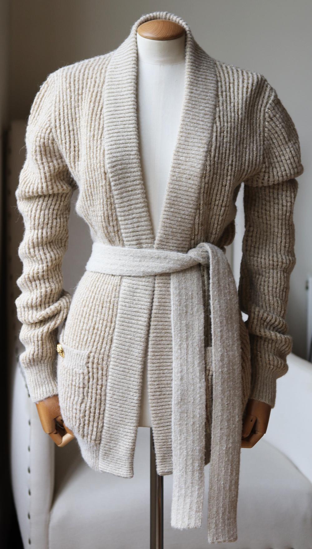 Er ist aus einer kuscheligen Woll-Alpaka-Mischung gestrickt und hat einen optionalen Bindegürtel:: der die lockere Silhouette abrundet:: sowie Taschen:: die Ihre Hände warm halten. 
Beige und goldfarbenes Woll-Alpaka-Gemisch. 
Schlüpft auf. 
30%