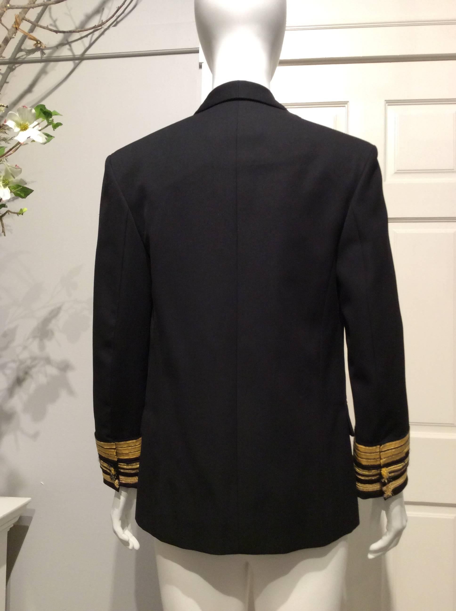 Black 100% wool gabardine Balmain uniform inspired jacket with unfinished gold ribbon trim on sleeves and crested pewter silver  buttons. Narrow tuxedo collar lapels. Mock double breasted - it closes with a small metal hook on the left side. Two