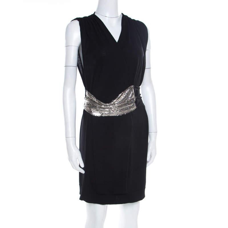 Become a trendsetter and make heads turn in this stylish mini dress from Balmain! The black creation is made of 100% wool and features a flattering faux-wrap silhouette. It flaunts a chainmail panel detailing on the waist and comes with a