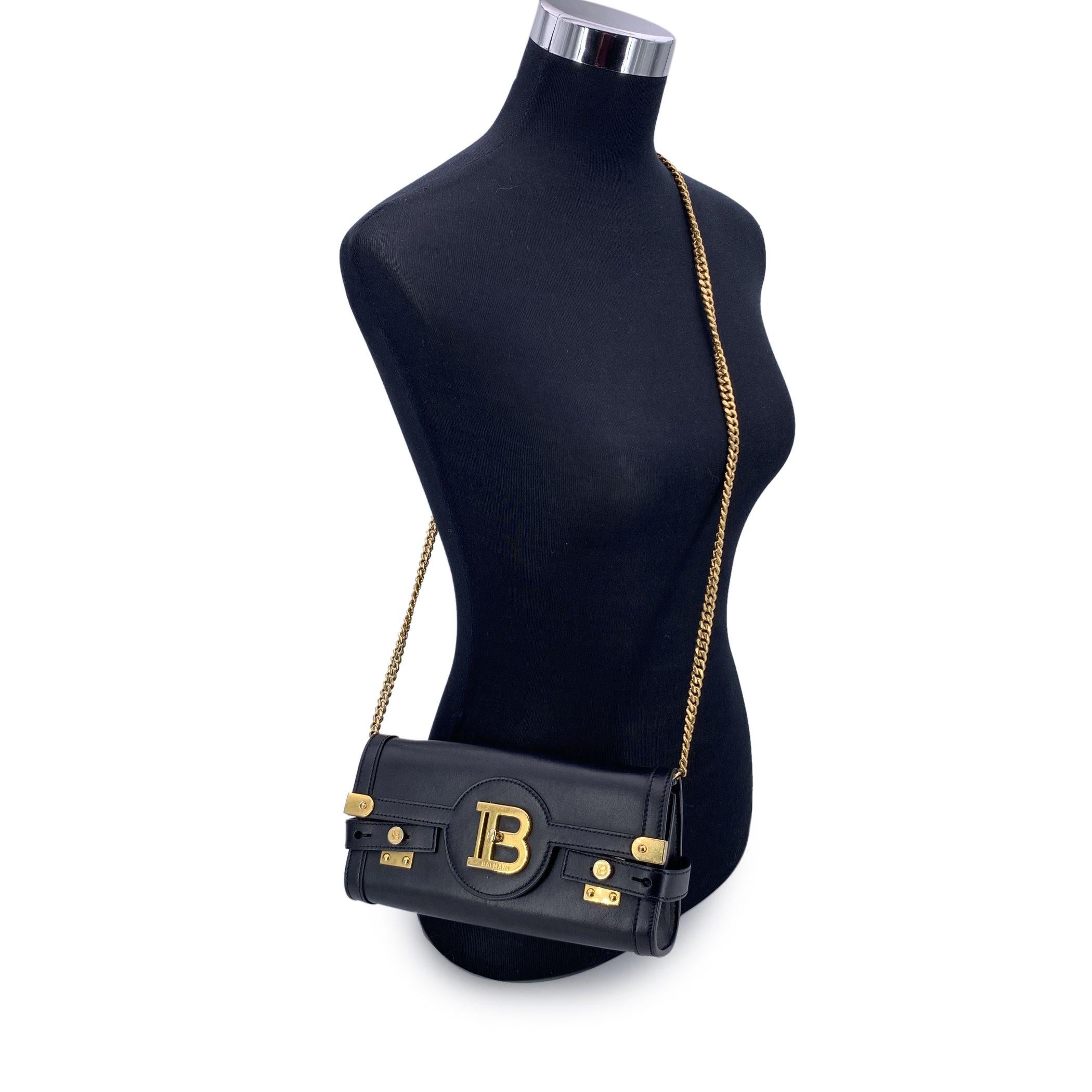 Die Balmain B-Buzz 23 Pochette aus schwarzem Leder ist ein kühnes und zugleich raffiniertes Accessoire, das die charakteristische Mischung aus Struktur und Eleganz des Hauses widerspiegelt. Mit ihrer länglichen Silhouette und goldfarbenen Beschlägen