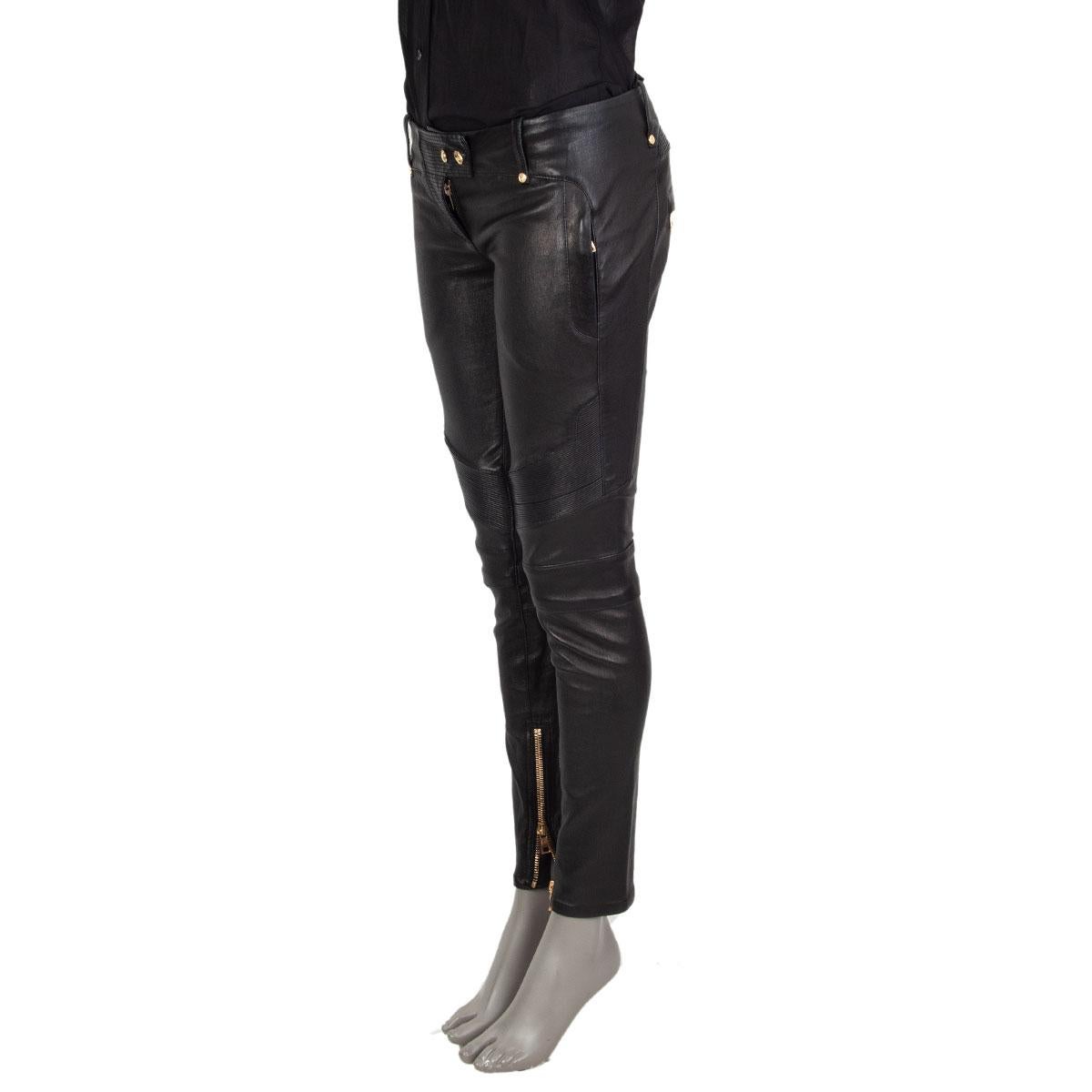 100% authentische Balmain Biker-Hose aus schwarzem Lammleder mit goldfarbenen Knöpfen mit Adlerprägung, Reißverschlusstaschen vorne, Reißverschlusstaschen hinten und Manschettenreißverschlüssen. Auf der Vorderseite mit einem Reißverschluss und