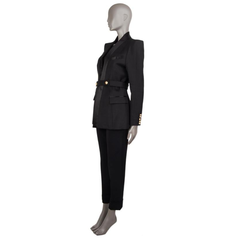 Balmain satin-trimmed tuxedo jacket in black wool (100%). With chest pokcet, two flap pockets on the sides, slit on the back, and buttoned cuffs. Comes with matching belt with two snap closures in signature dragon gold-tone buttons. Lined in black