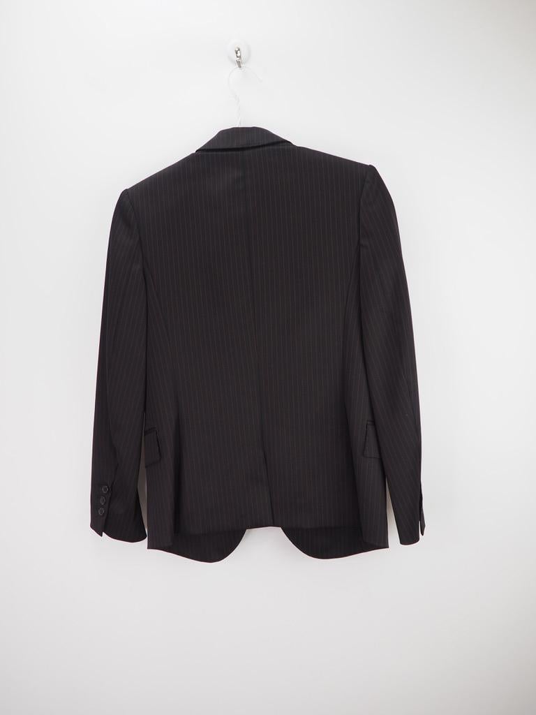 Balmain black wool blazer with fine red stripes. Fitted cut with a tailored colour, long sleeves, 1 slant pocket on the left chest, crest embroidered with a crown. Slit on the back, with a flap patch pocket on the hips, 1 inside pocket, centre