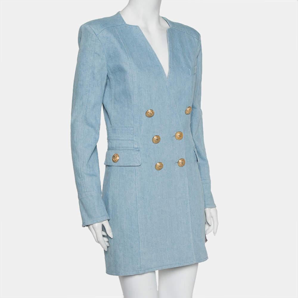 A blue denim dress by Balmain that you can effortlessly match with statement sandals, pumps, or boots. The mini dress brings a double-breasted front with gold-tone button details, a V neckline, three pockets, and a back zip closure.

