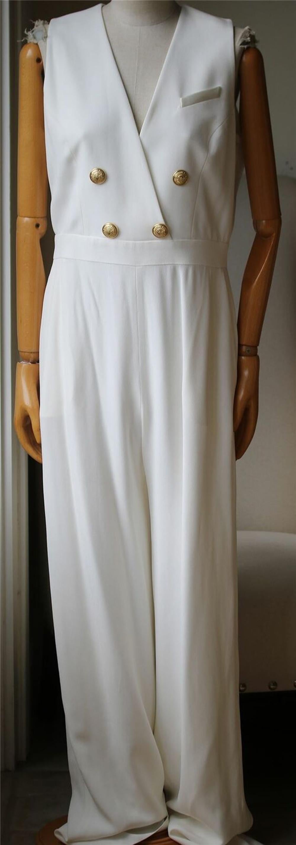 This jumpsuit suits all ladies, with its fluid white crepe silhouette, plunging neckline and signature lion-embossed buttons. White crepe. Zip fastening along back. 52% viscose, 48% acetate. Comes up small.

Size: FR 44 (UK 16, US 12, IT