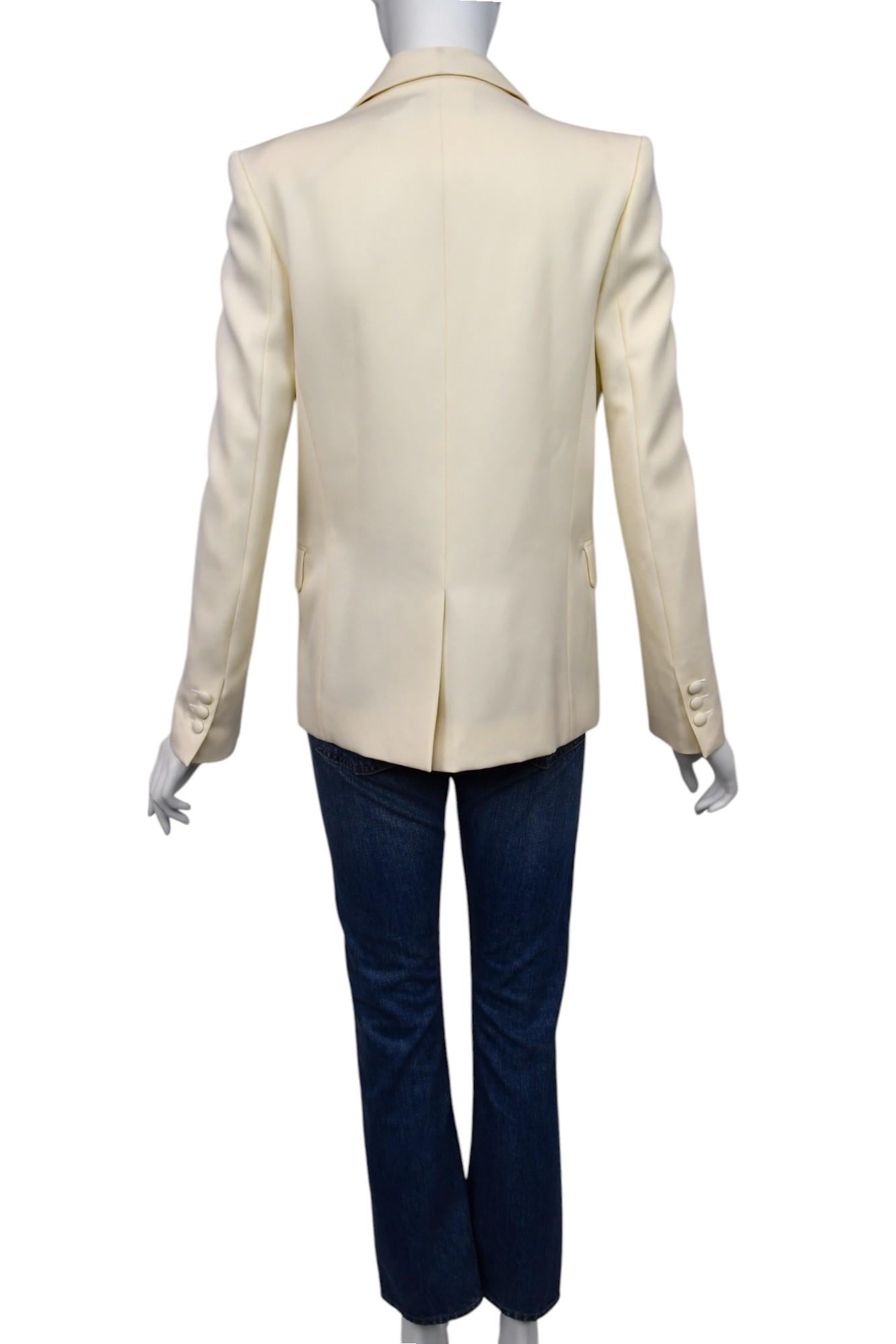 Raffinato e versatile, questo blazer Balmain è realizzato in un tessuto liscio color crema con un'elegante silhouette a monopetto. Il design è caratterizzato da un risvolto a scialle, tasche con patta e bottoni in tonalità ricoperti di tessuto per
