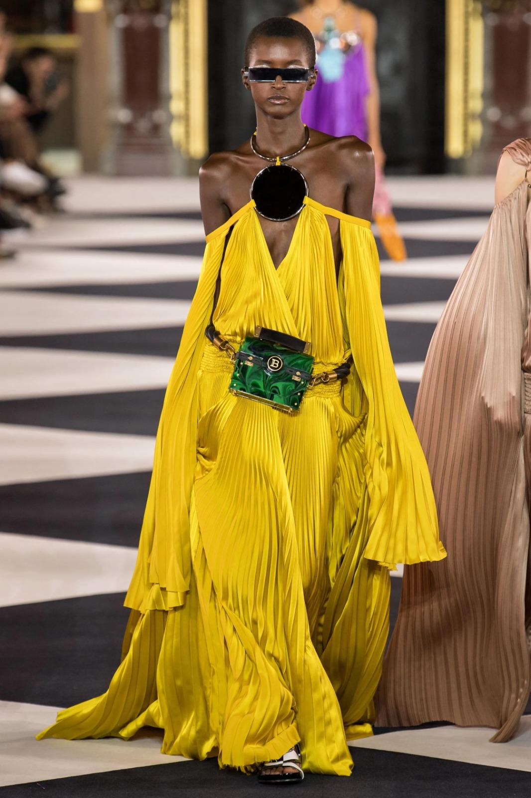 BALMAIN - Langes gelbes Kleid, das vollständig von Sonnenstrahlenfalten bedeckt ist. Silbernes Metallhalsband mit schwarzem runden Bakelit. Größe 38FR angegeben. Frühjahr-Sommer-Kollektion 2020, unter der künstlerischen Leitung von Olivier