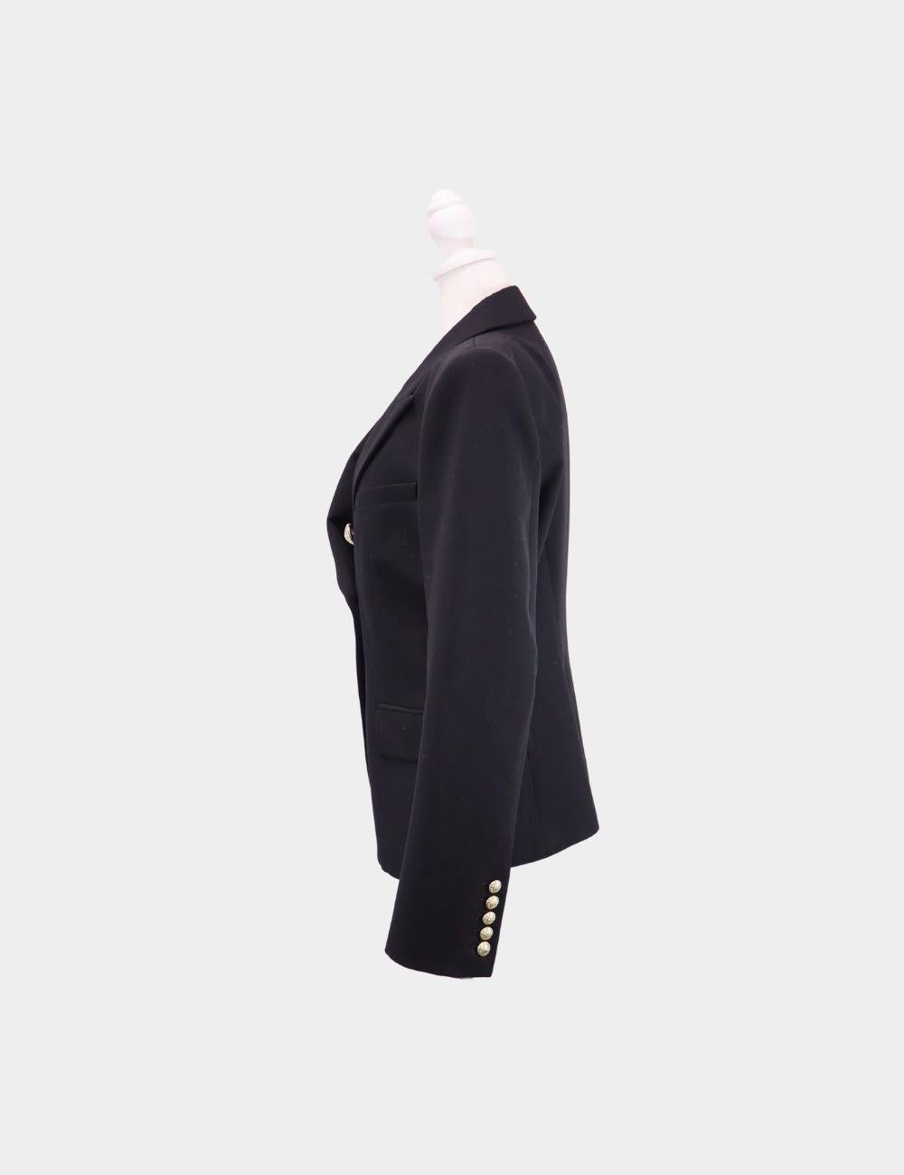 Power dressing at its finest—this Balmain black double-breasted blazer is a signature piece from the iconic French fashion house. Featuring a sharply tailored silhouette, strong padded shoulders, peak lapels, and the unmistakable gold-tone embossed