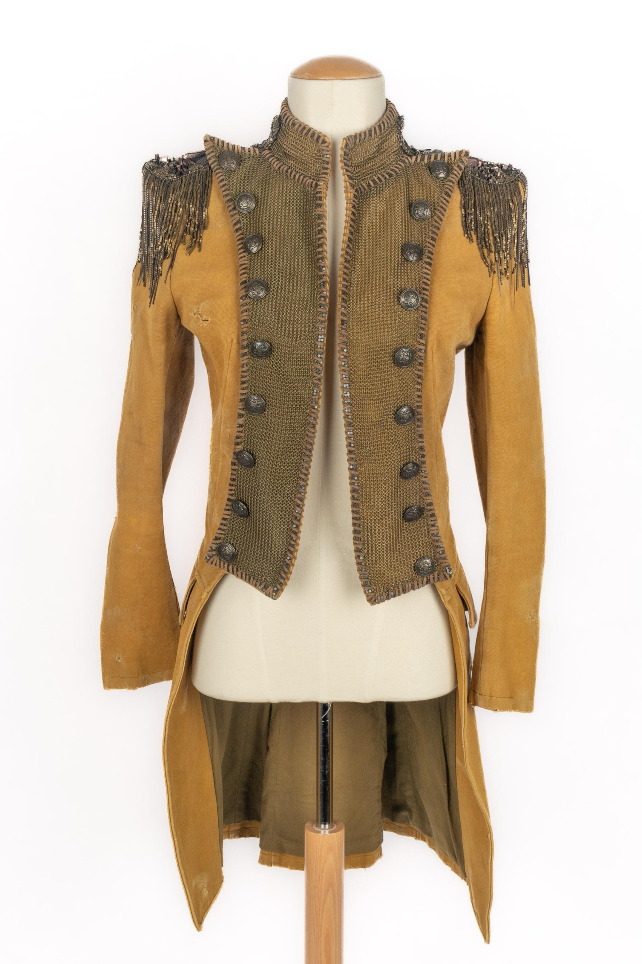 Fabrice - Giacca militare in tessuto invecchiato con fori e risvolti da cappotto legati con bottoni in ottone lavorati. Spalline ornate con paillettes, perle, frange di perle e catene. Non è indicata la taglia, si adatta a una 36FR. Collezione