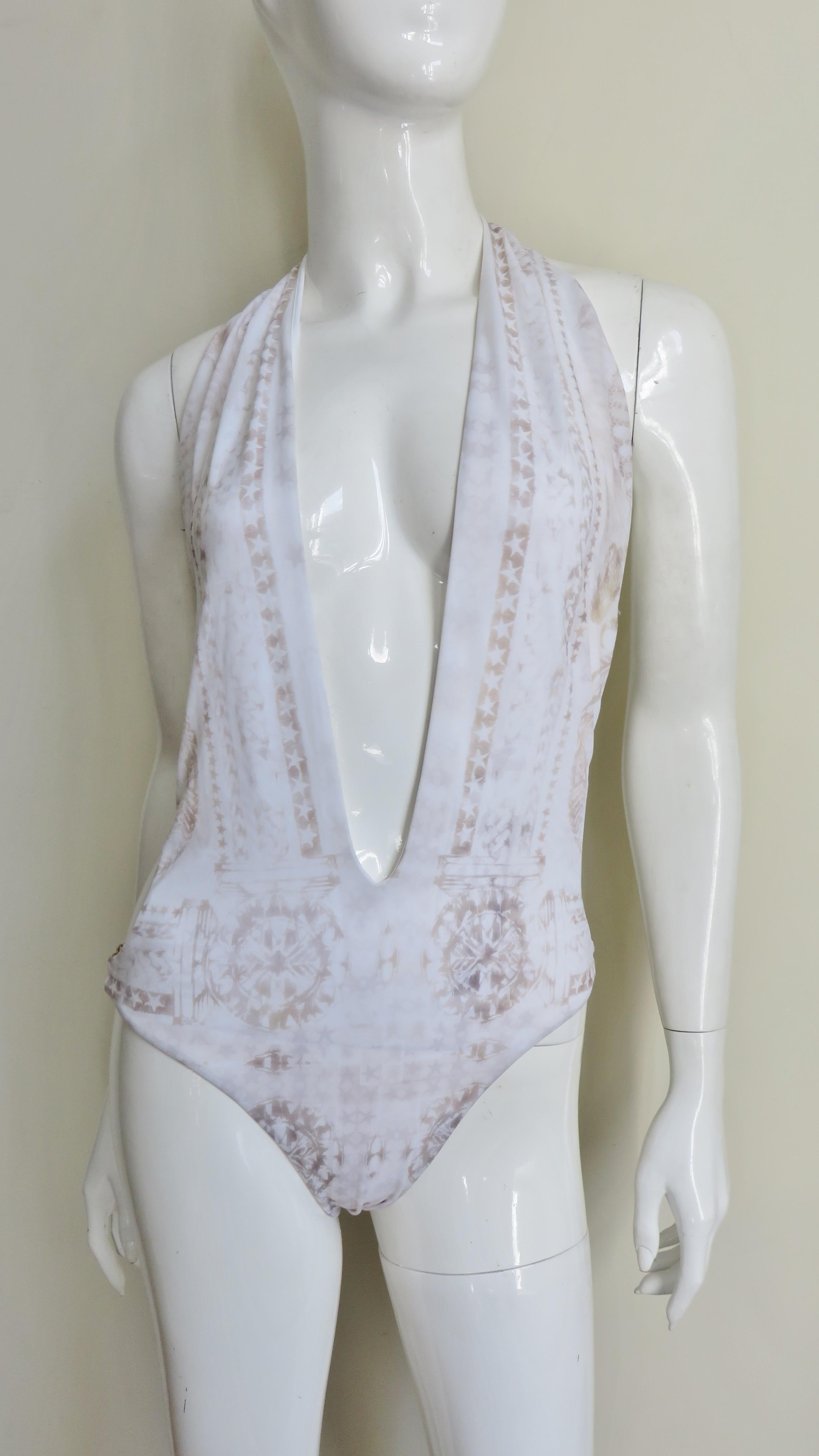 A fabulous plunging Balmain swimsuit in white with a grey abstract geometric pattern.  It has a low plunging neckline which close at the back of the neck with a gold metal clasp.  There are ties a the side bust that tie in the back and the same