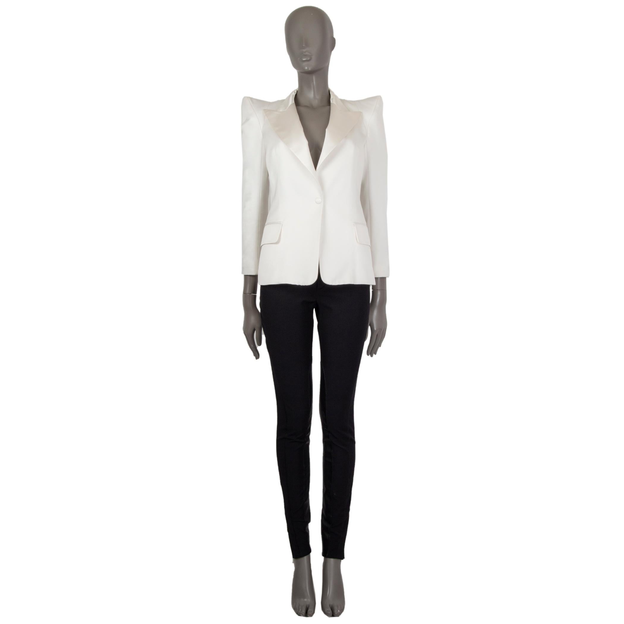 Balmain tuxedo blazer in off-white cotton (51%), polyester (39%), and silk (100%). With satin peak collar, peak shoulders, two flap pockets on the sides, and buttoned sleeves. Closes with one fabric-lined button on the front. Lined in off-white
