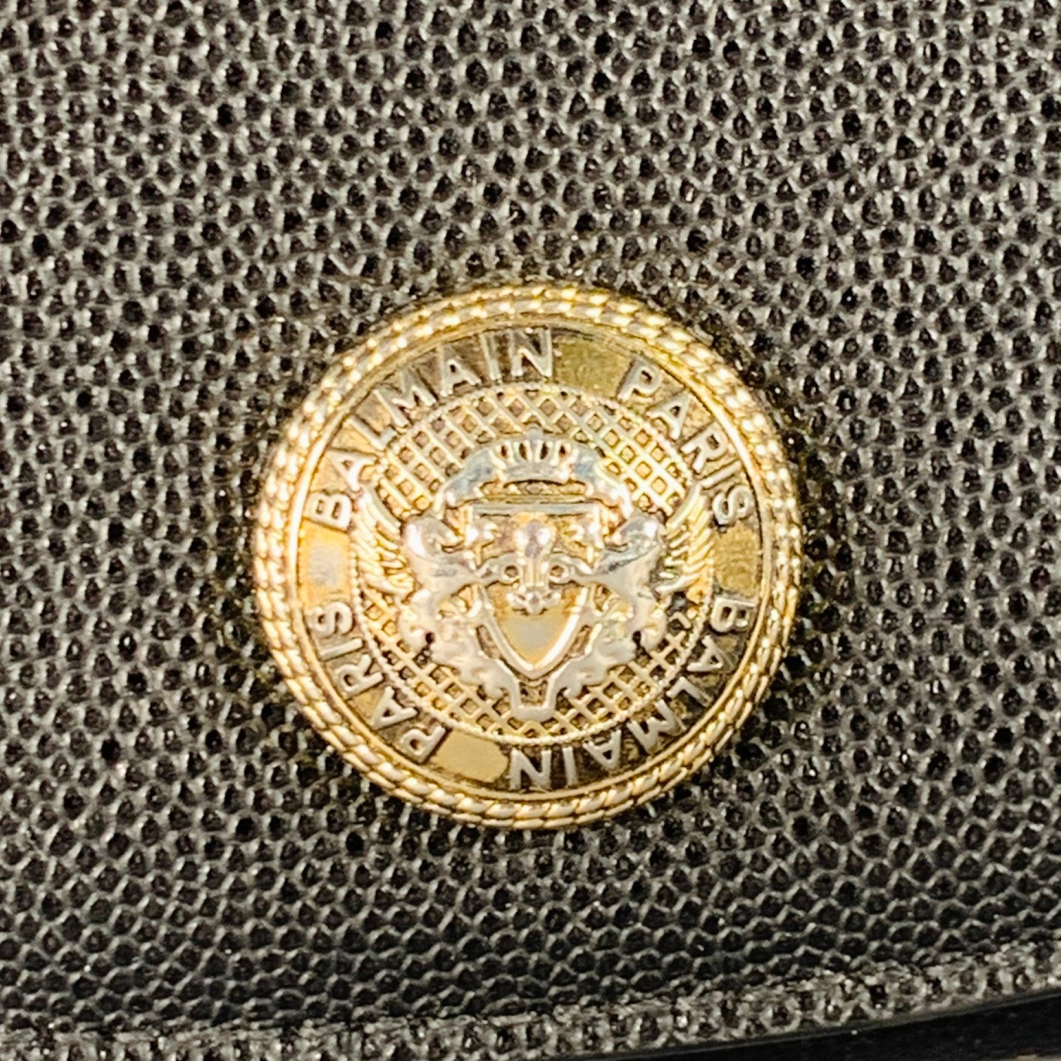 Balmain portefeuille sac à main
en cuir grainé noir, avec un logo en métal doré, une lanière en chaîne en métal doré et une fermeture à bouton-pression. Fabriqué en Italie. Très bon état.  

Mesures : 
  Longueur : 7.25 pouces Hauteur : 4.75 pouces