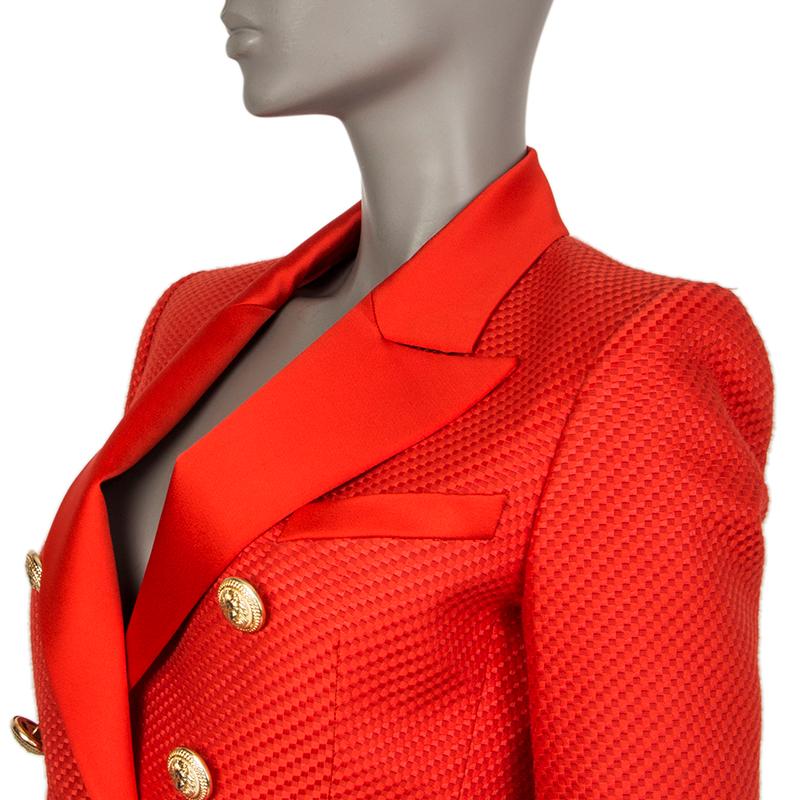 Balmain check-tweed double-breasted blazer in red cotton (80%) and silk (20%). With satin peak collar, chest pocket, two flap pockets on the sides, padded shoulders, and buttoned cuffs. Closes with signature lion-head buttons in gold-tone metal.
