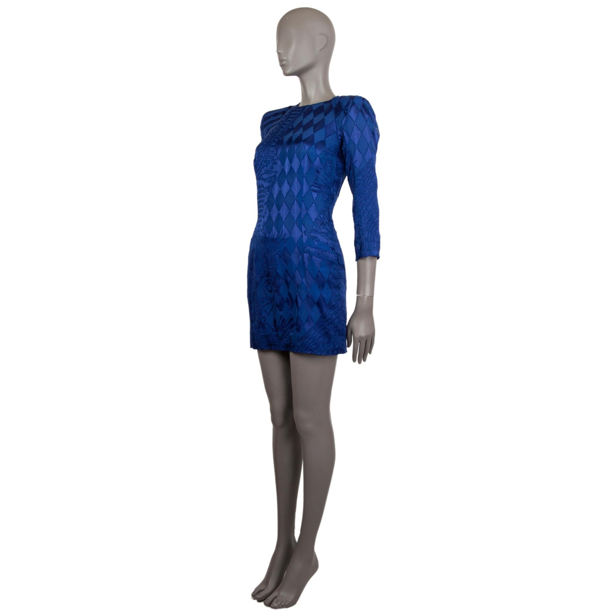 Balmain long-sleeve devore mini dress in royal blue viscose (85%) and silk (15%). With crew neck and padded shoulders. Closes with silver-tone zipper on the back. Lined in royal blue silk (100%). Has been worn and is in excellent condition. 

Tag