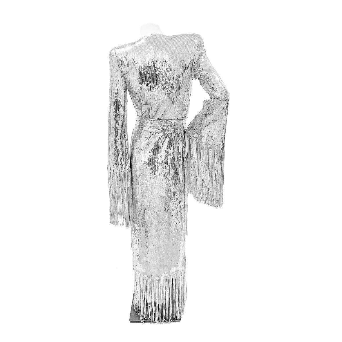 Silver Sequin Fringed Gown by Balmain
Made in Italy
Silver sequins
Sequin fringe detail
Large silver Balmain button detail
Front side nap button closure
Large asymmetrical V neckline
Large cut out detail in front of dress
Long sleeve
Gown comes with
