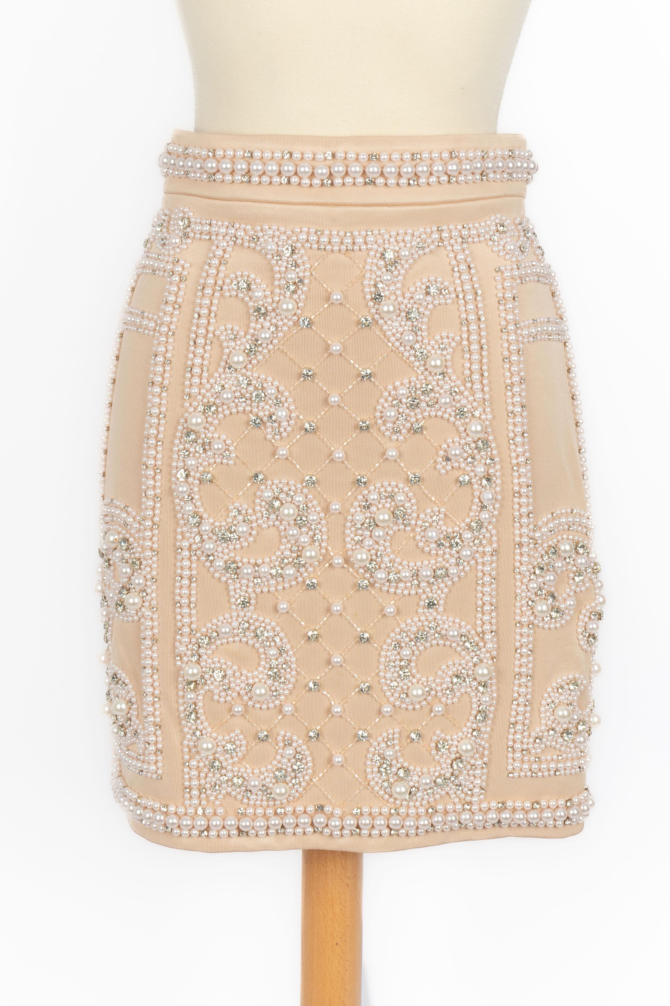 BALMAIN - Falda beige bordada con costumep earls y strass. Se indica la talla 36FR.

Estado:
Muy buen estado

Dimensiones:
Cintura: 32 cm - Caderas: 44 cm - Largo: 46 cm

SKU:FJ103