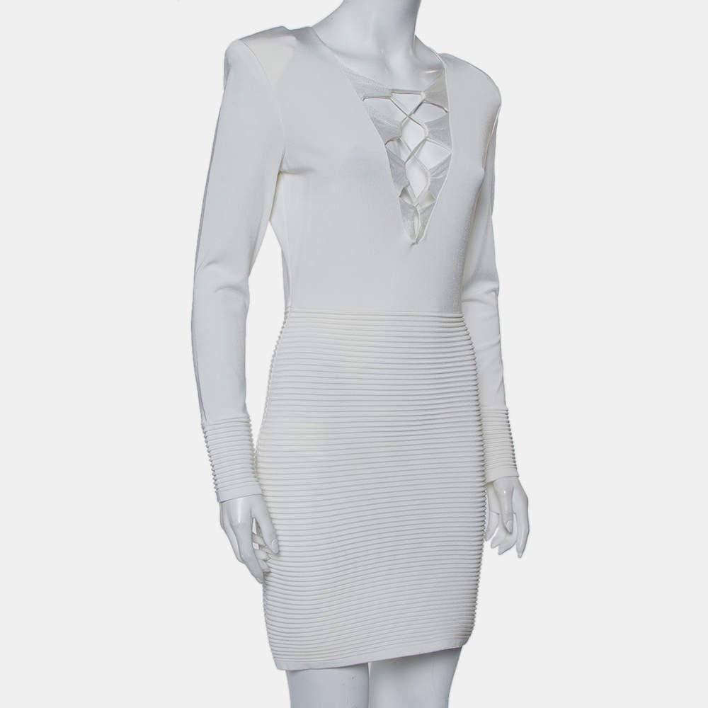Dieses weiße Minikleid von Balmain setzt mit seinem tiefen Ausschnitt und den Bindedetails ein Highlight. Das Kleid hat einen Reißverschluss am Rücken und gerippte Akzente an den langen Ärmeln und am Rock. Stylen Sie ihn mit auffälligen