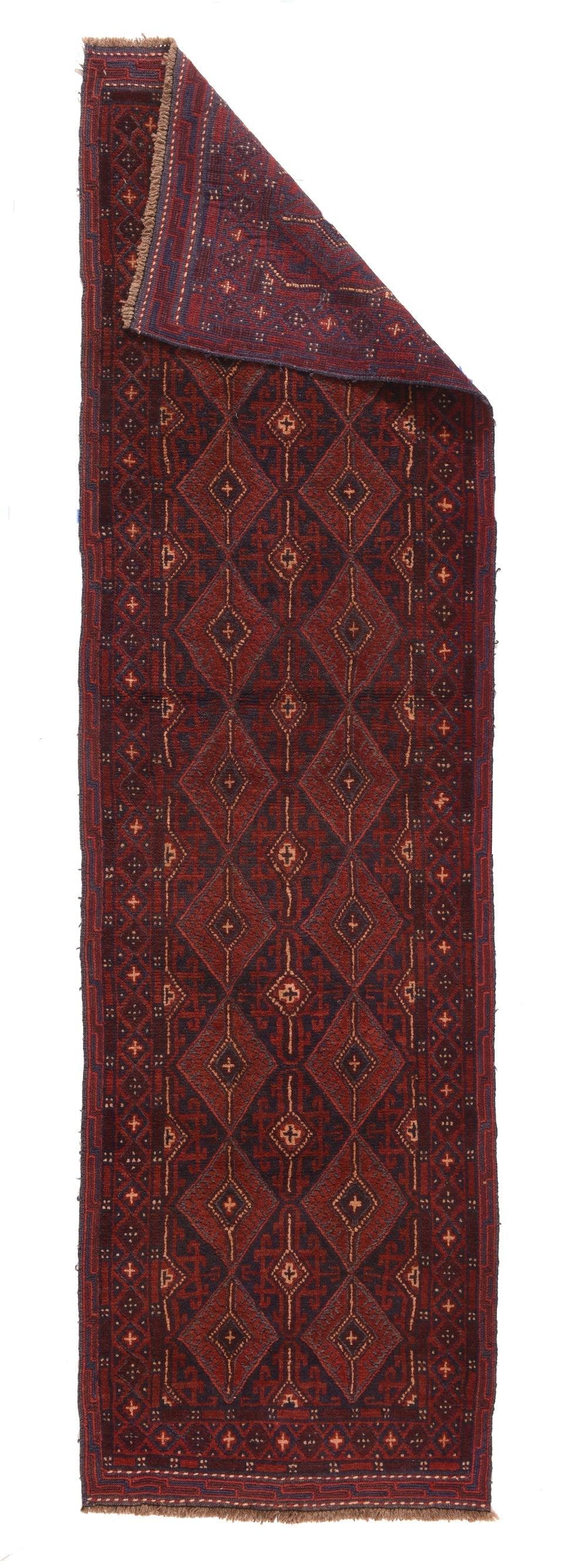 Balouch Runner 2'4'' x 8'3''.  Il campo blu sostiene due colonne di losanghe verdi unite con interni a losanghe uncinate e annidate. Tra e lungo i lati ci sono quadrati aperti rossi uncinati completi e parziali. Bordo principale di una catena di