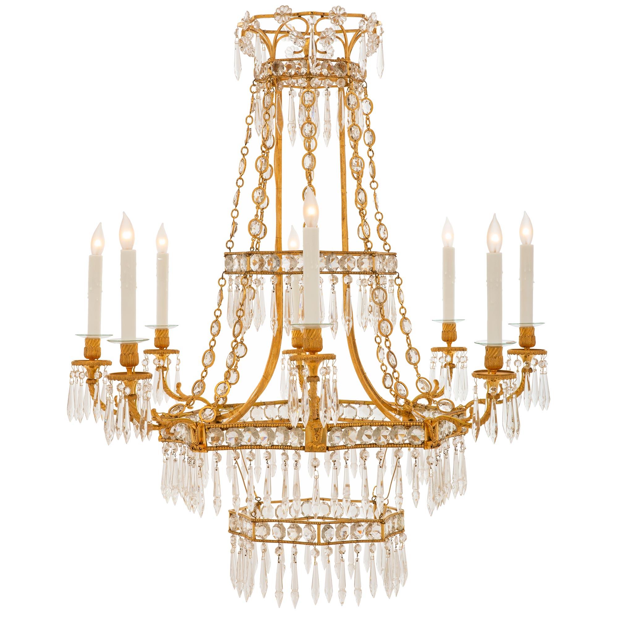 A striking and extremely decorative Baltic 19th century Louis XVI st. crystal and ormolu chandelier. The eight arm chandelier is centered by a most elegant octagonal crown like bottom tier with lovely fitted cut crystals and beautiful prism shaped