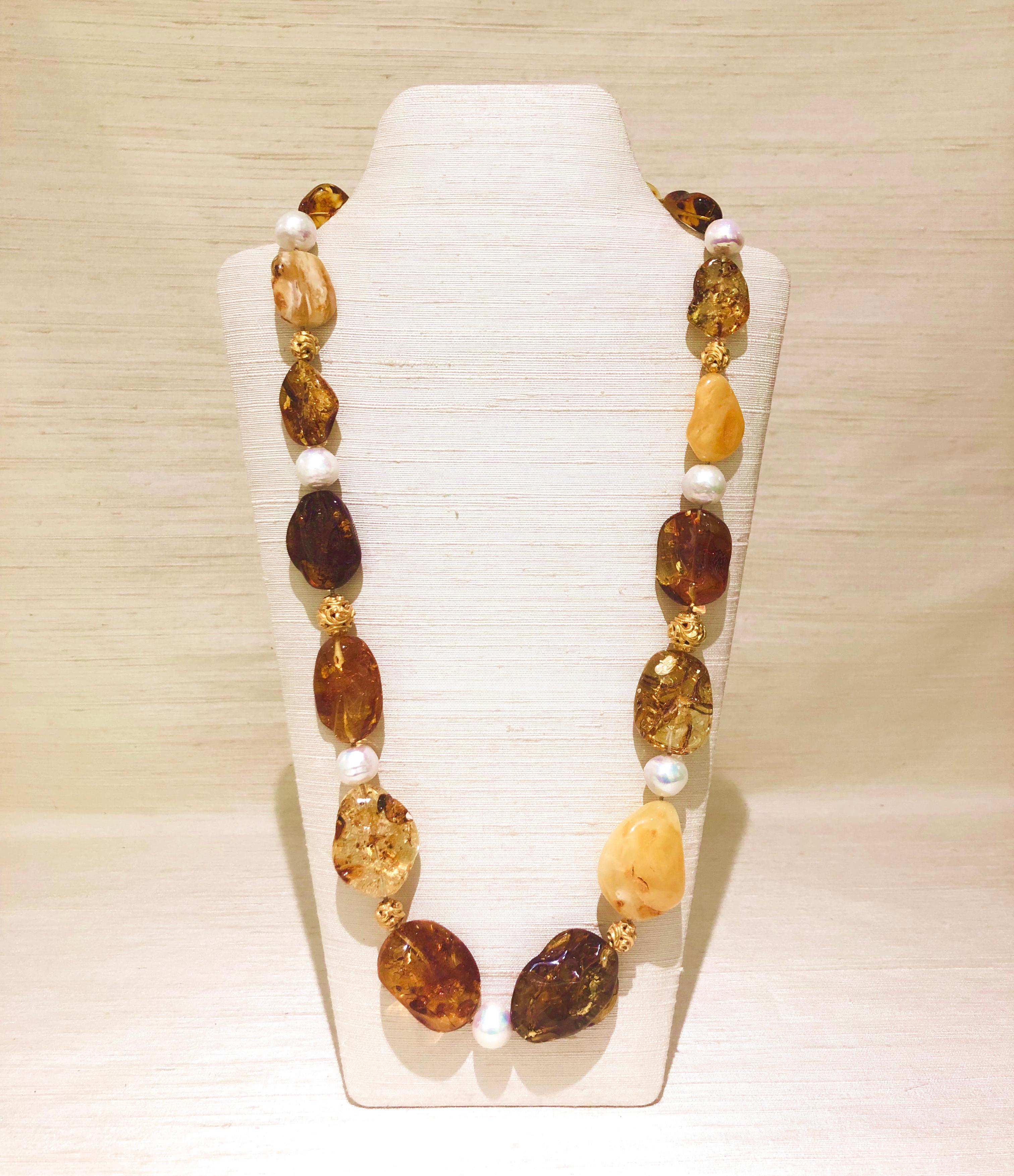 A charming  29”L (74cmL) necklace with pebble Baltic amber beads ranging from 5/8”L (1.5cmL) to 1 ¾”L (4.5cmL) in butterscotch, lemon, honey, cognac and cherry colours, handcrafted 18 karat vintage carved gold beads, Baroque freshwater pearls, and