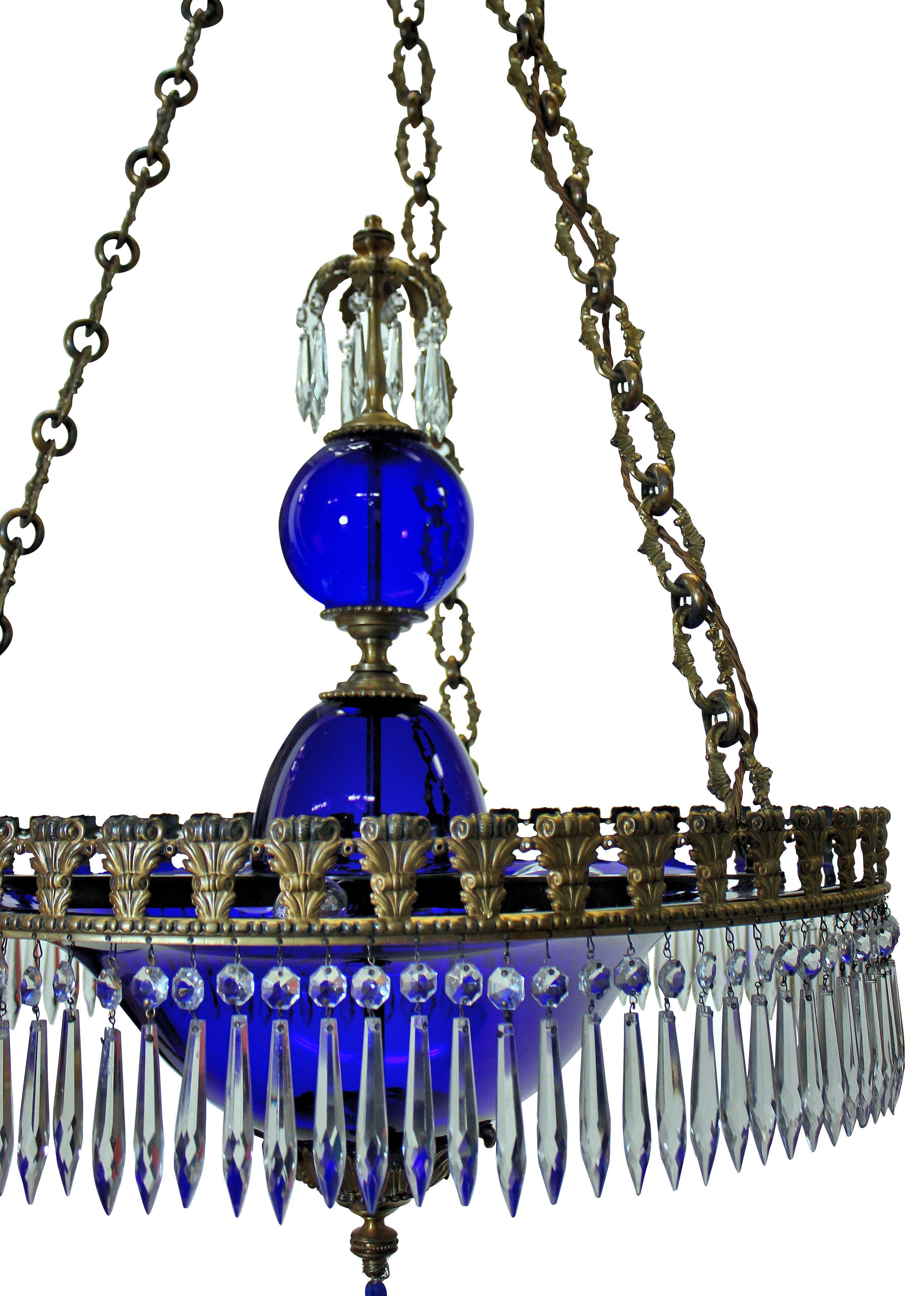 A fine Baltic blue glass Neo-Classical chandelier of corona form, in gilt bronze, with anthemion and acanthus decoration and decorative chains. Hung with clear glass pendants and blue finials.