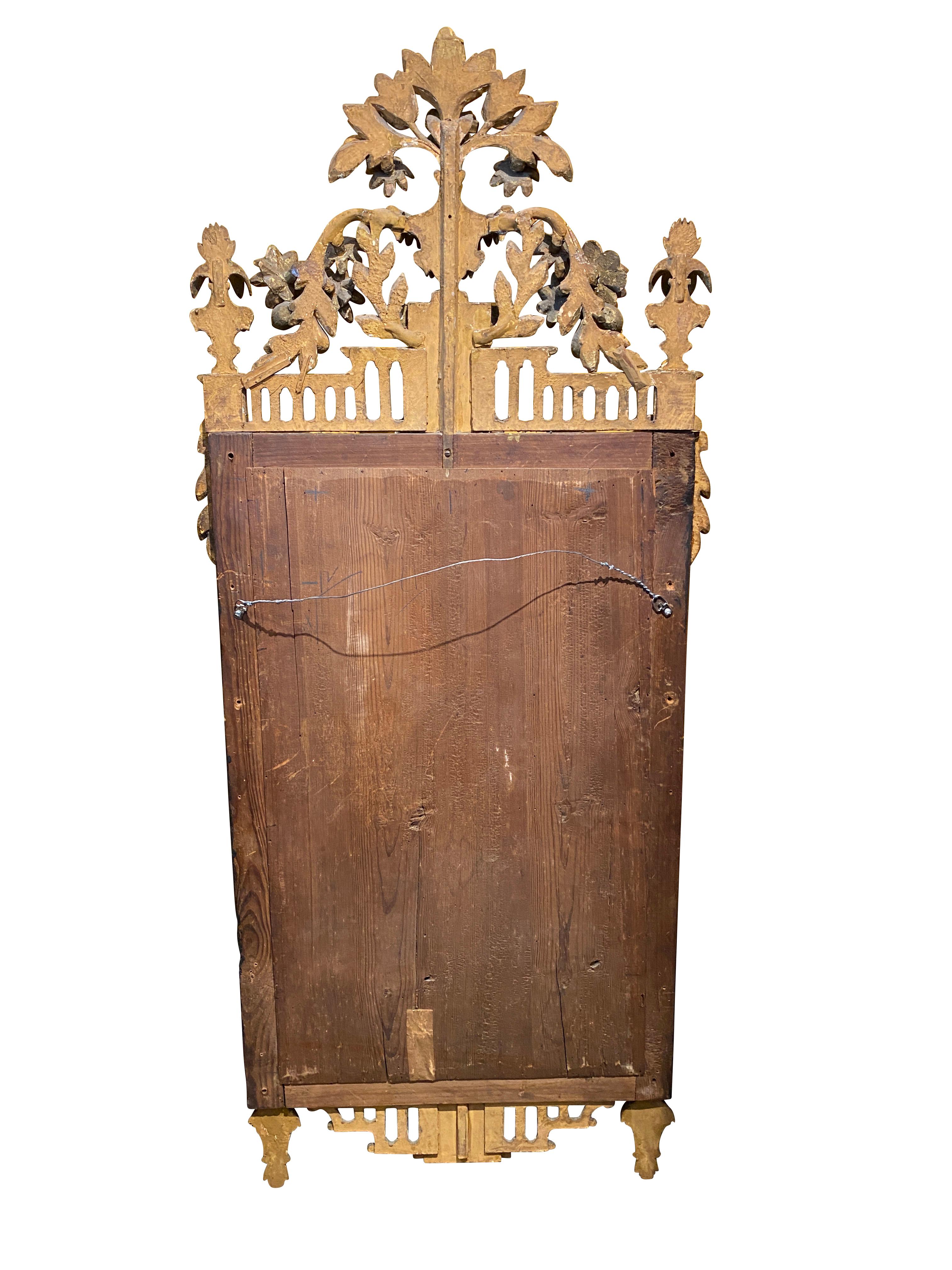 With an urn with festoon of flowers and leaves flanked by trailing festoons and flanked by finials over trelliswork and rectangular walnut frame with gilded beaded edge surrounding a mirror plate, rosettes on the corners with trellis base detail