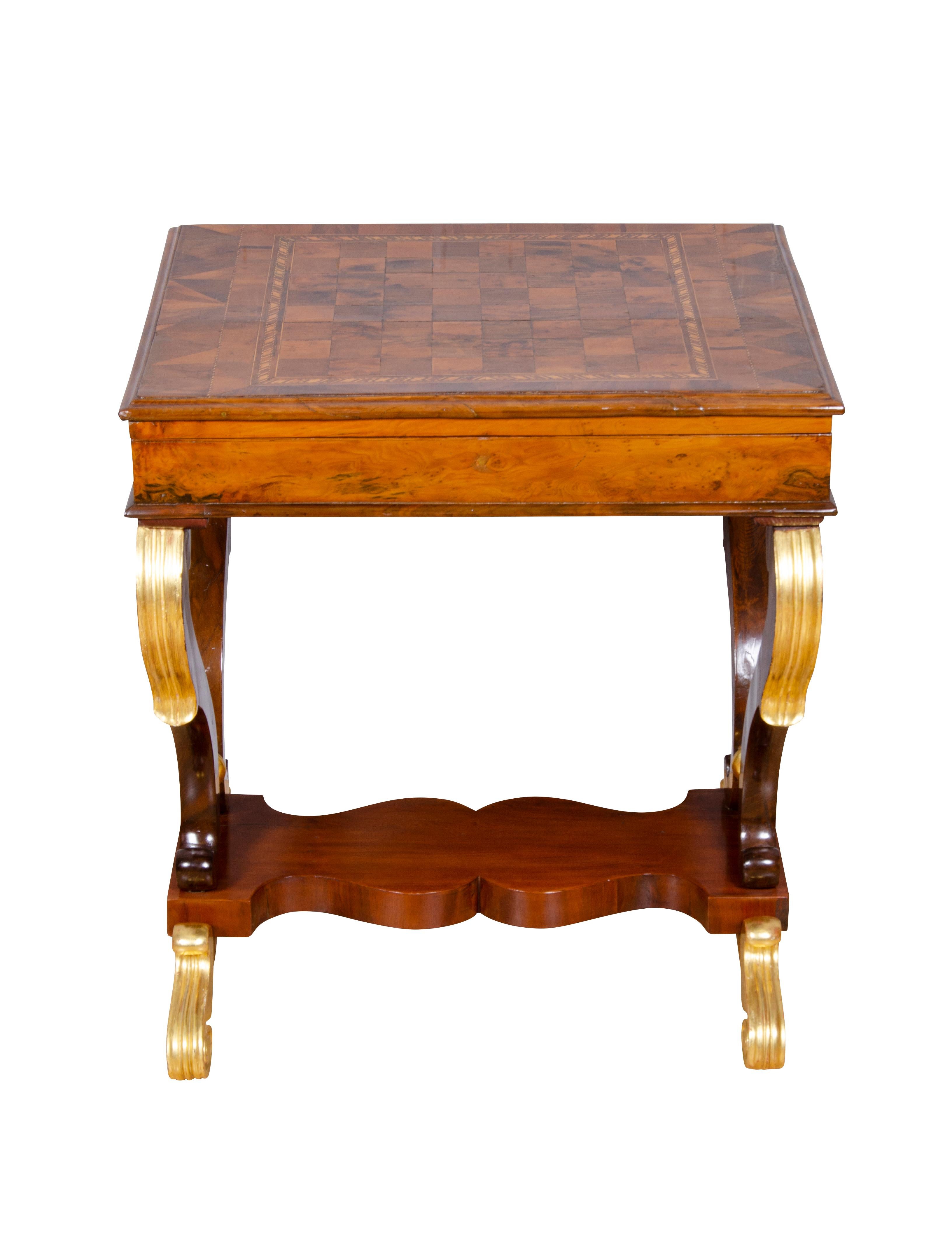 Rectangular removable top with chess board opening to a backgammon table with two game piece compartments, raised 
on scrolled legs with gilded details, shaped stretcher and ending on scroll feet.