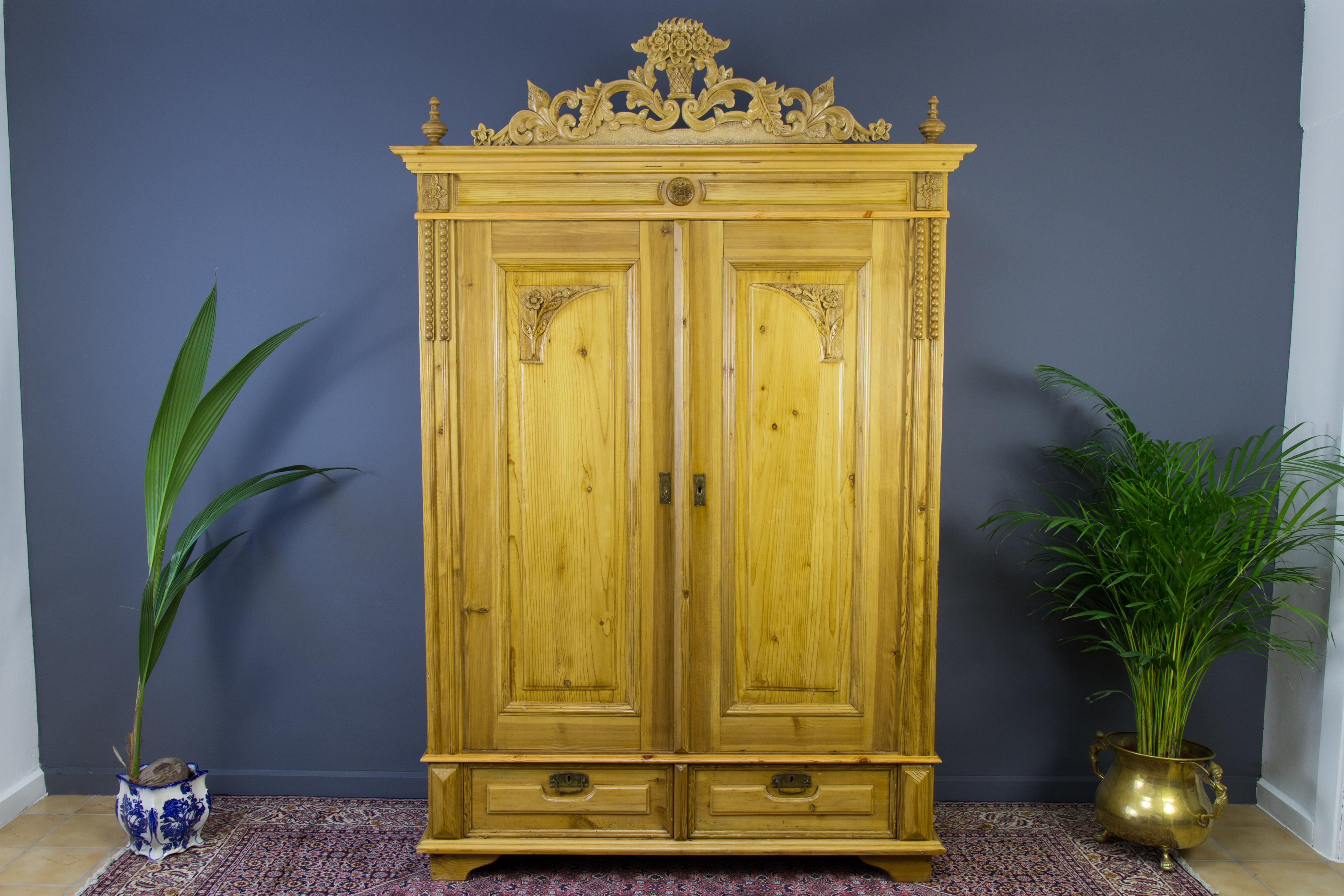 Baltic Pine Two-Door Armoire with Carved Flower Crown, the 1920s
Beautiful early 20th-century two-door armoire of Baltic pine with extensive floral carvings. This antique wardrobe has three shelves, two drawers below, and one interior drawer. One