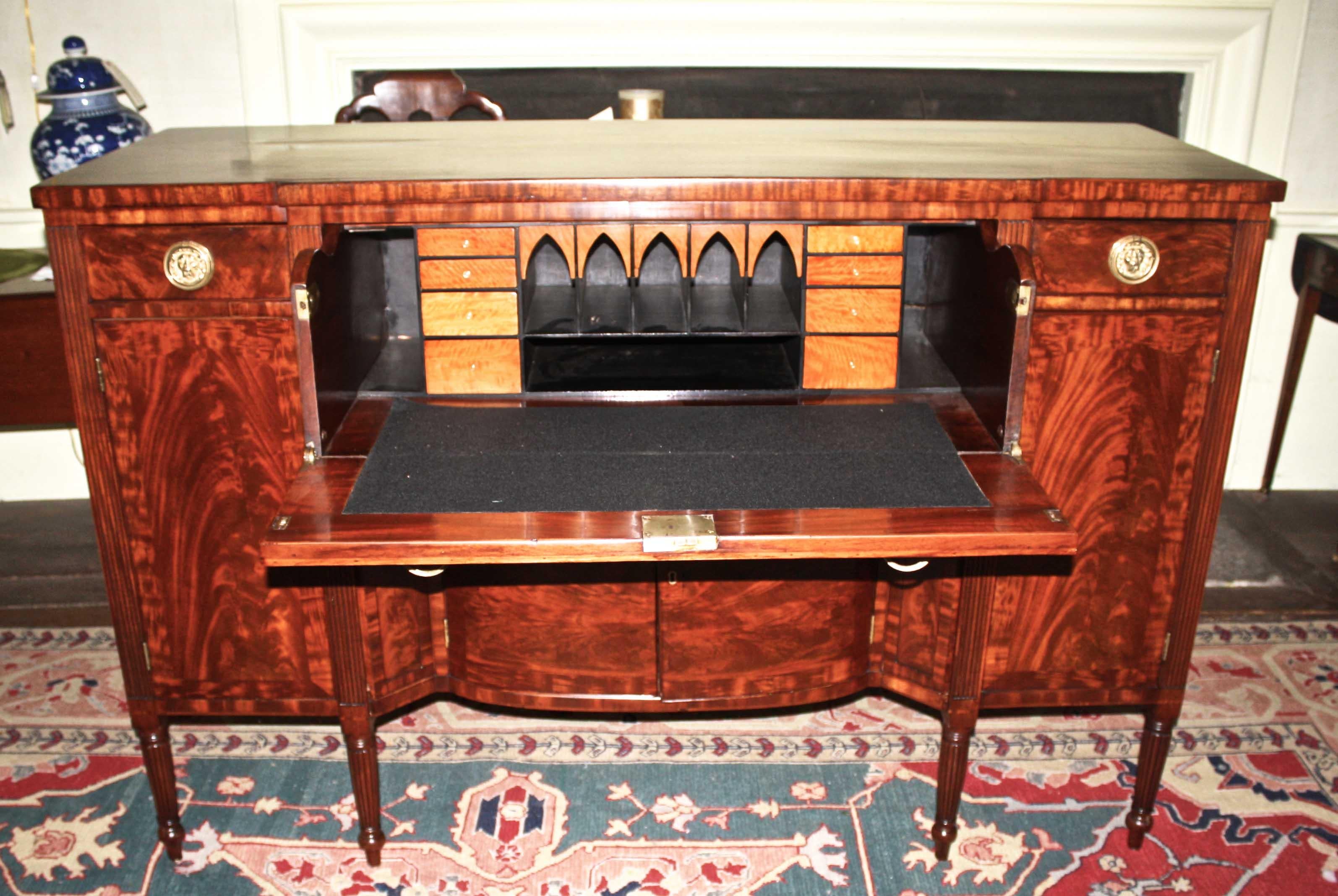 A Bankson and Lawson 'School', Sheraton manner sideboard with a English influenced fall-front butler's secretary drawer. Exceptionally vibrant crotch and flame mahogany veneers and bandings; the secretary desk is fitted with sharply contrasting