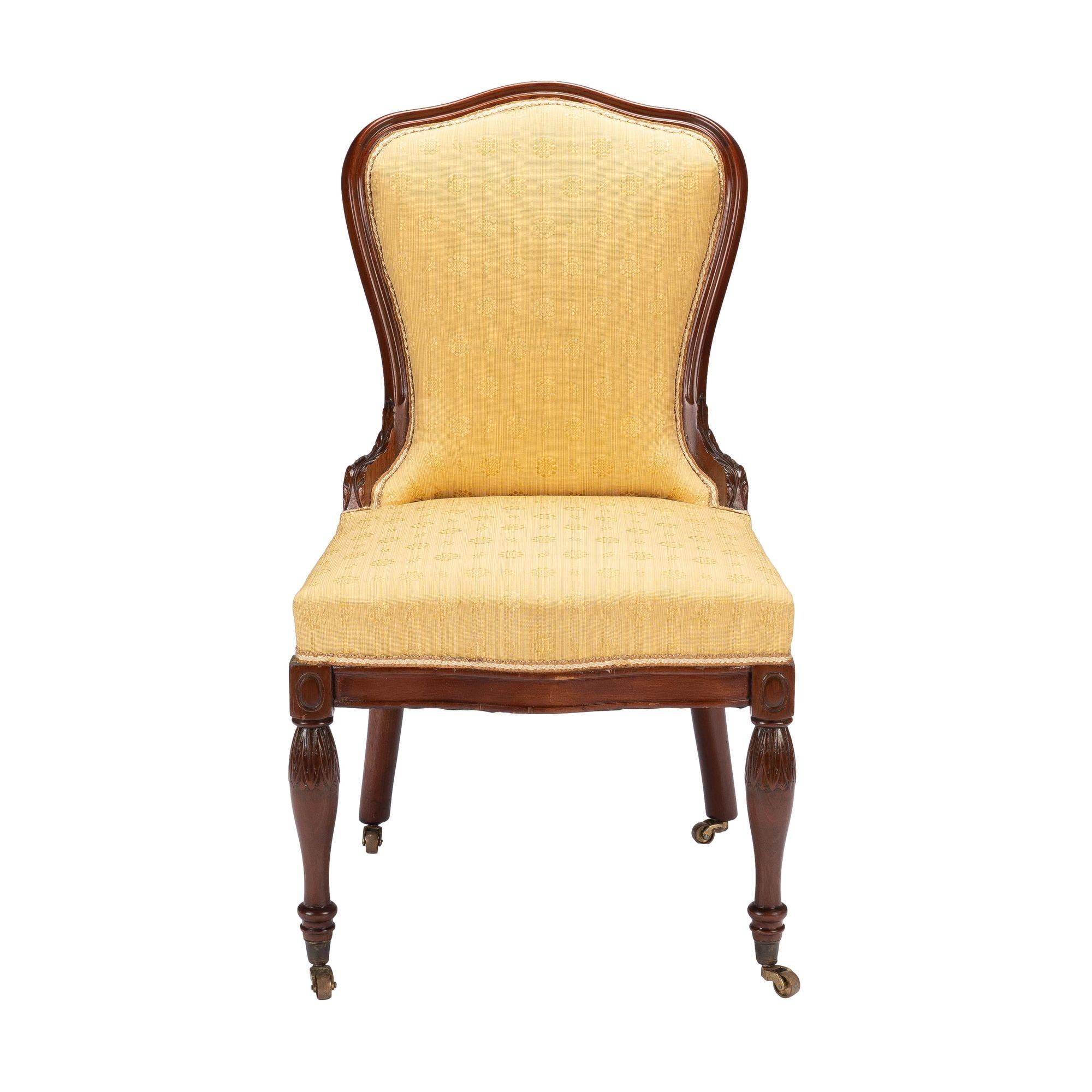 Baltimore Louis XVI Revival upholstered mahogany slipper chair. The chair features turned and carved front legs and raked rear legs. All legs rest in cast brass cup castors. The upholstered boxed seat is mounted to a conforming mahogany seat frame,