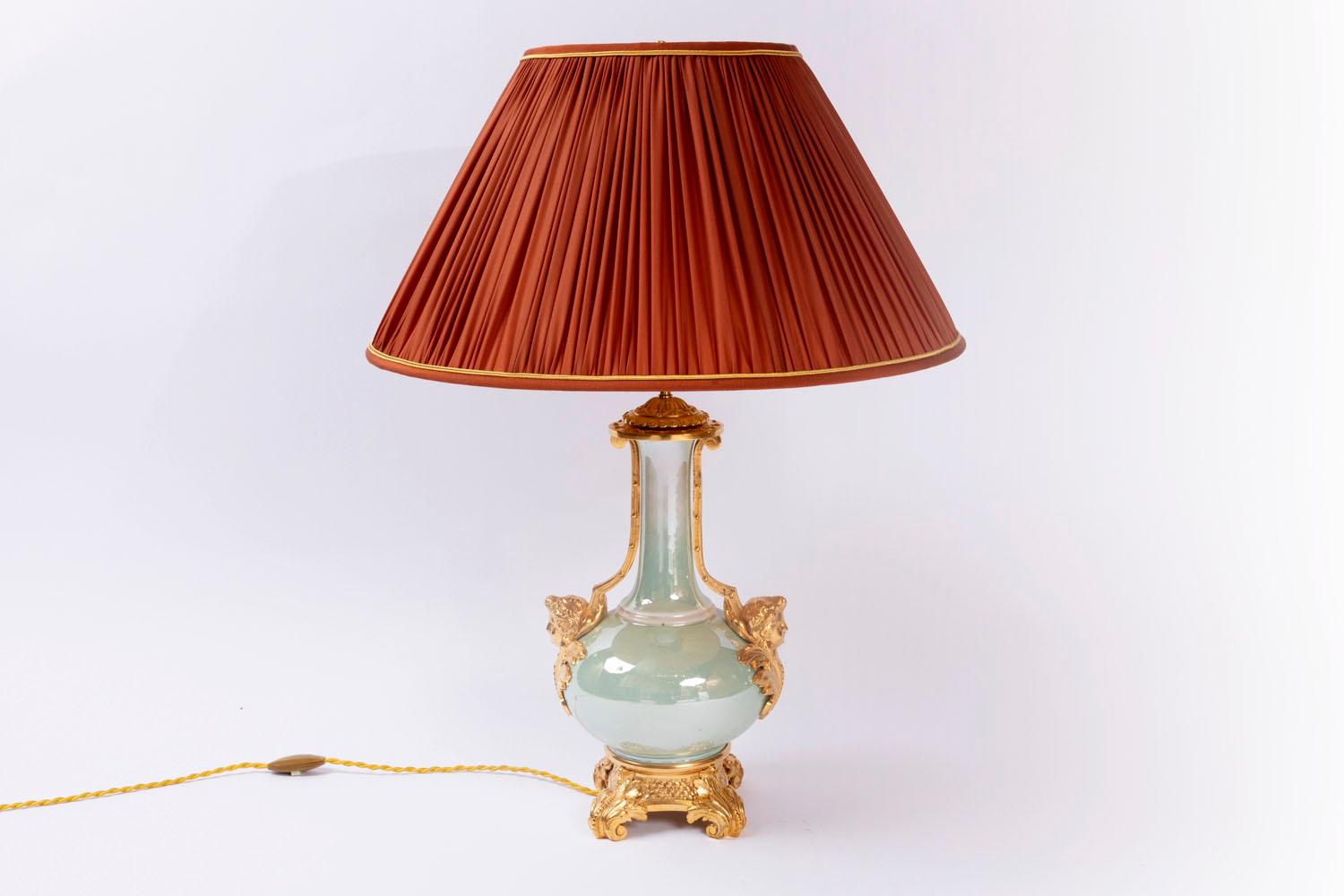 Baluster lamp in green iridescent porcelain standing on a gilt and chiselled bronze mount with a base decorated by small flowers on four wounded acanthus leave shaped foot.
The mount is fixed on the bulged body of the baluster thanks to two women