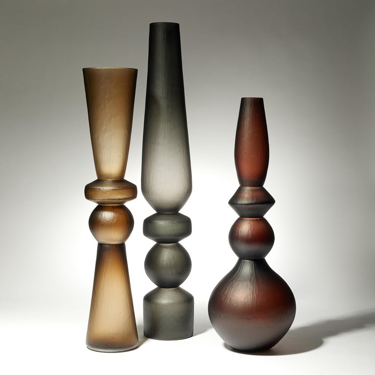 Dimensions shown are for the tallest vase, details of all three are below.

Four component Balustrade vase Trio is a group of olive, steel & brown hand blown glass vases, with 'Battuto' cutting finish, by the British artist Simon Moore. These can be