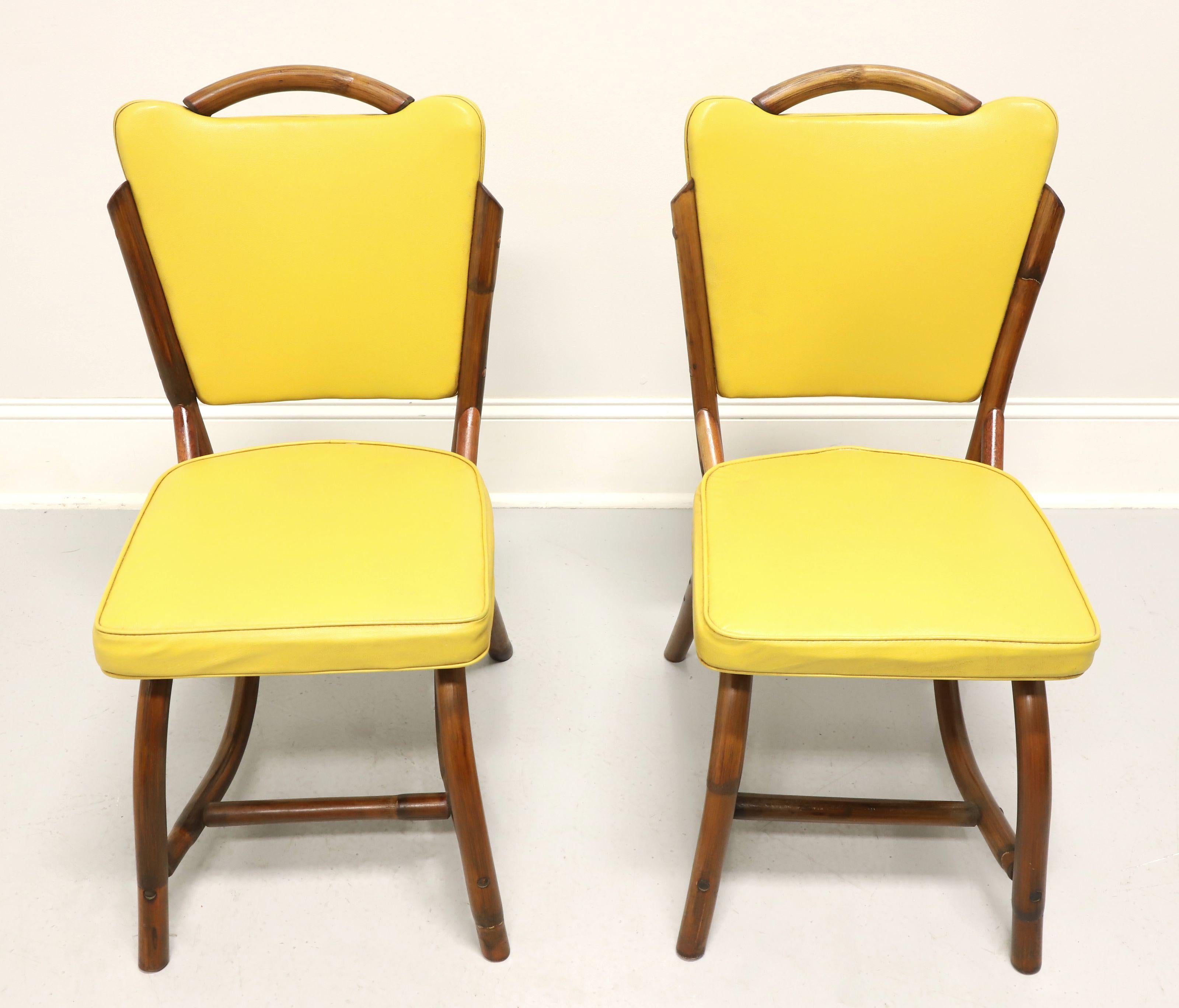 A pair of mid-20th century Coastal style dining side chairs by Bam-Tan Products. Rattan with a distinctive Mid-Century Modern style, rounded back with flared corner yellow colored vinyl upholstered backrest, arched legs and stretchers supporting